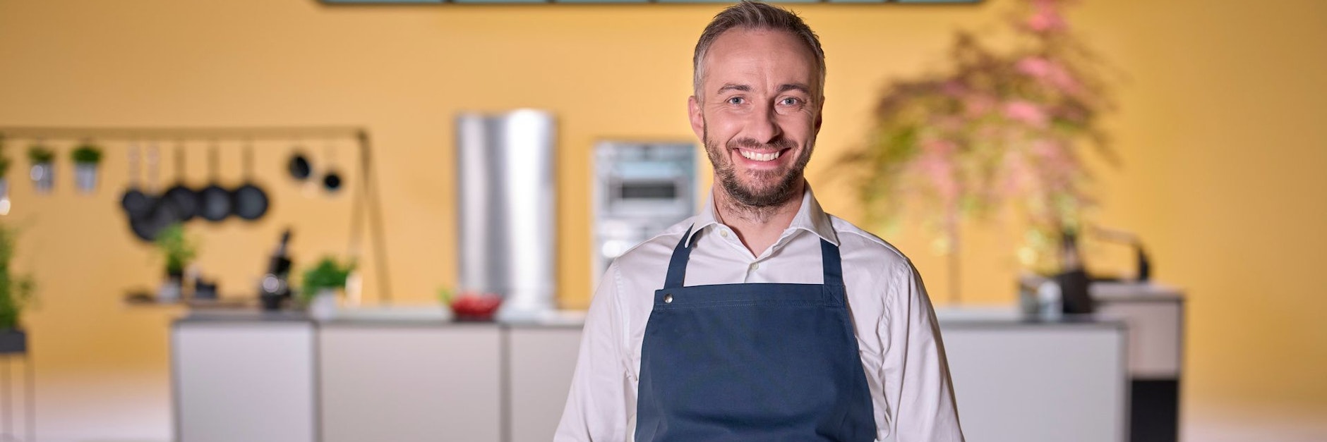 Moderator Jan Böhmermann steht in der Küche von „Böhmi brutzelt“, seiner Kochsendung bei ZDFneo, in der er mit wechselnden Gästen Essen zubereitet und plaudert.&nbsp;