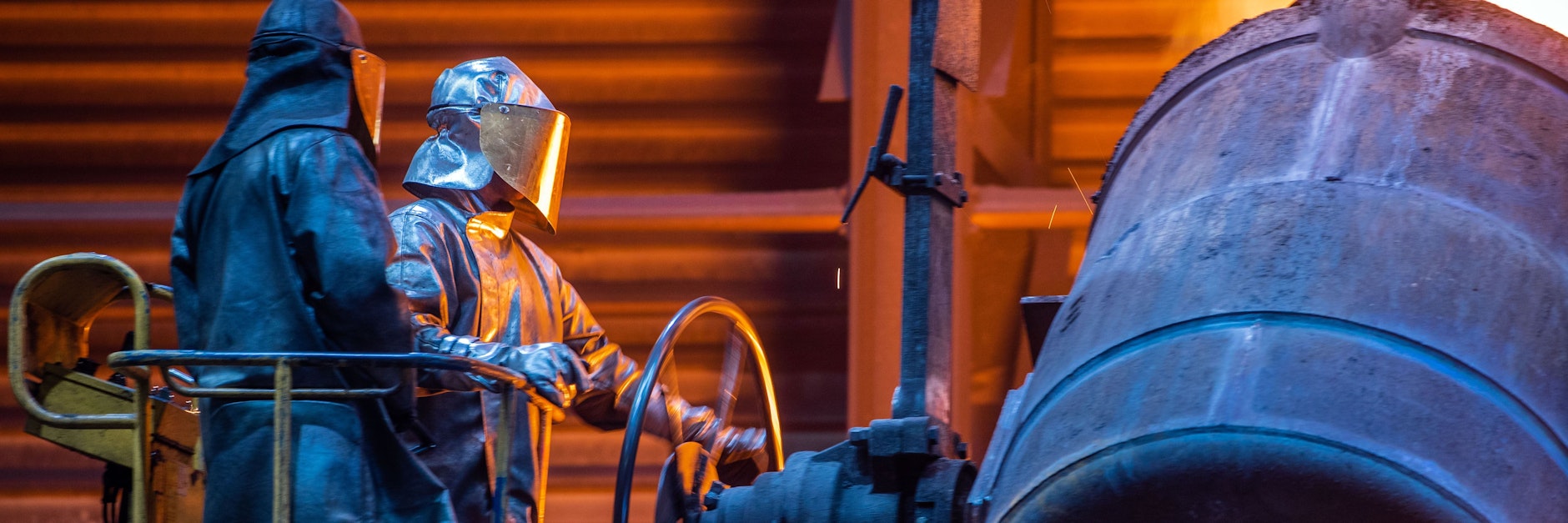 Arbeiter füllen in einer Eisengießerei flüssiges Eisen in Formen.&nbsp;