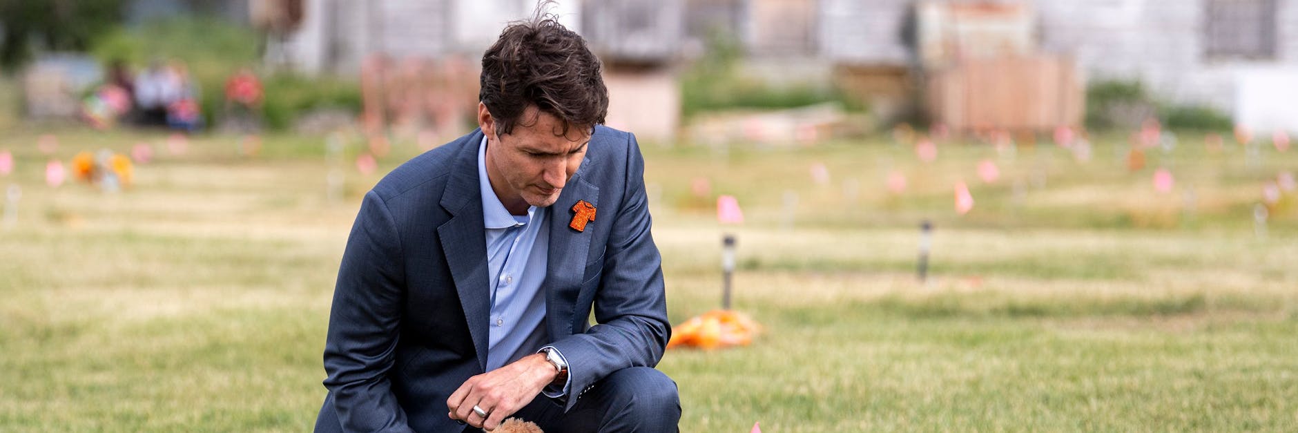 Justin Trudeau kniet an einer in den Boden gesteckten Flagge auf dem Gelände einer ehemaligen Internatsschule nieder.
