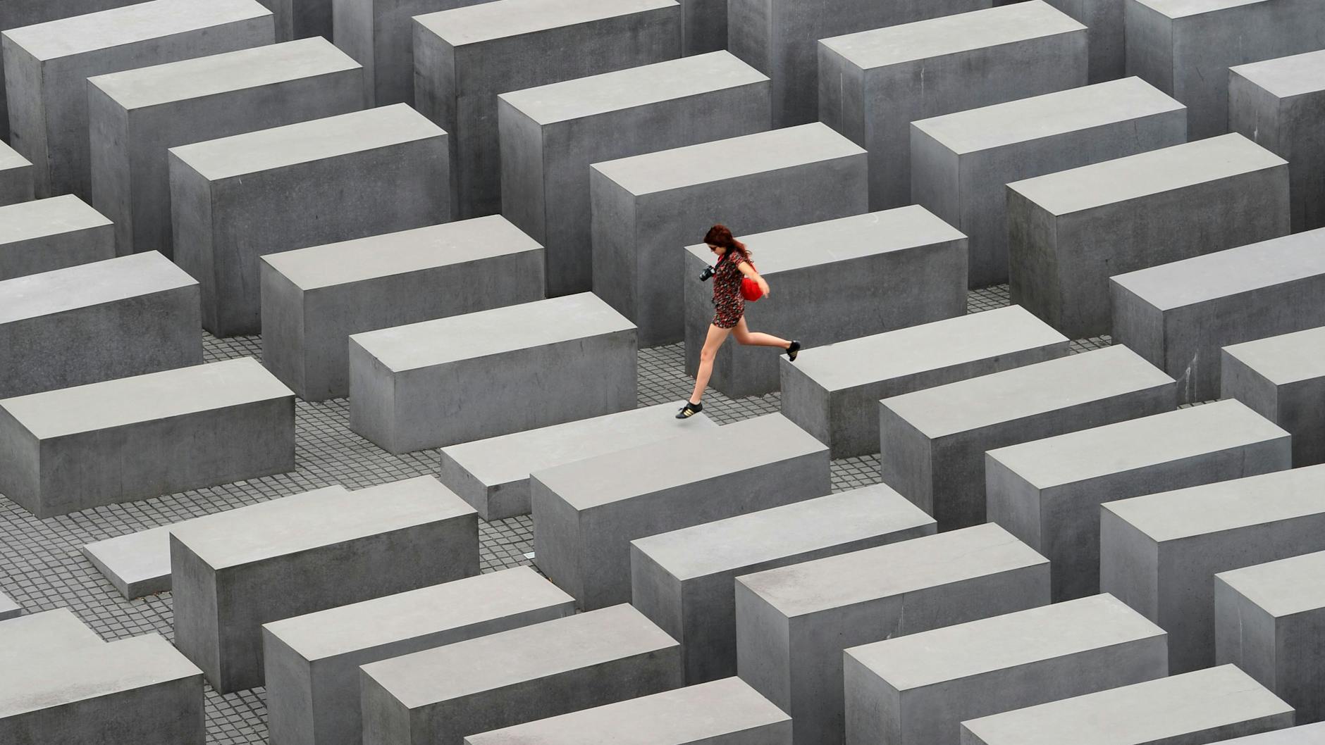 Eine junge Frau springt in Berlin über die Stelen des Denkmals für die ermordeten Juden Europas.