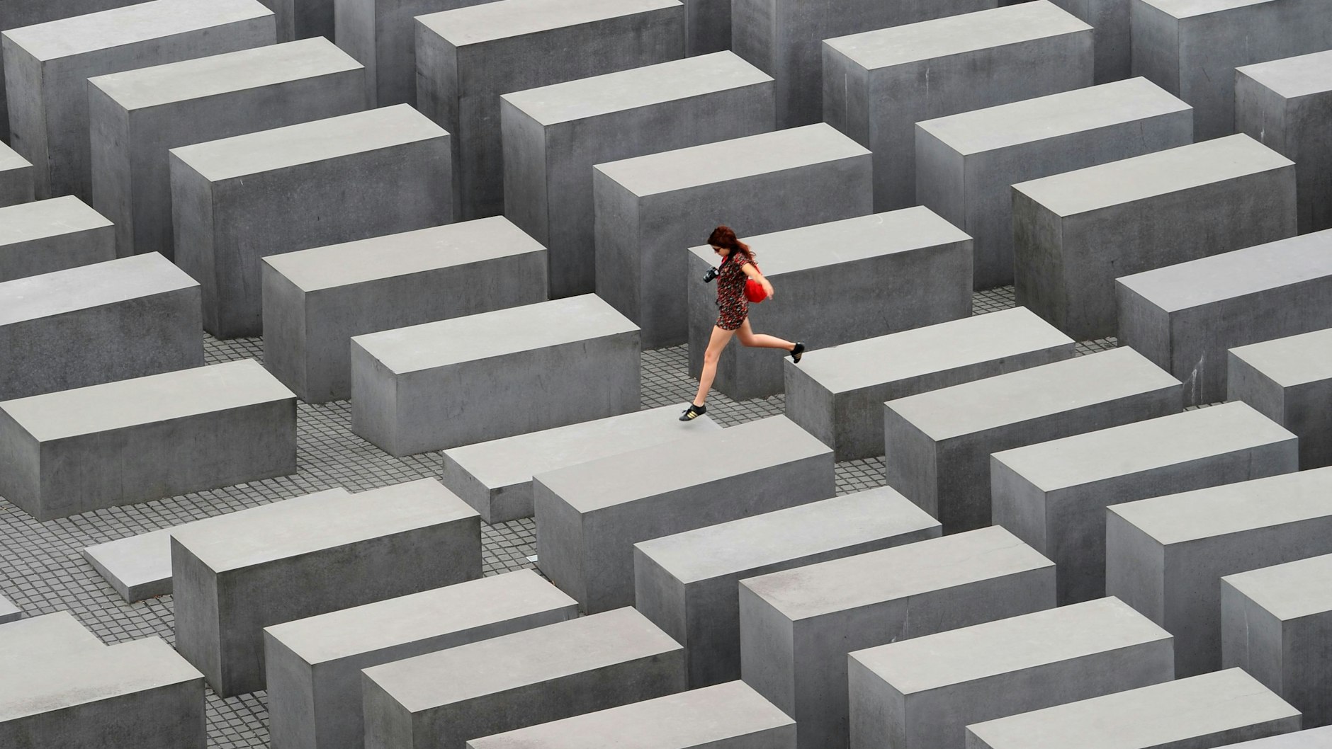 Eine junge Frau springt&nbsp; in Berlin über die Stelen des Denkmals für die ermordeten Juden Europas.