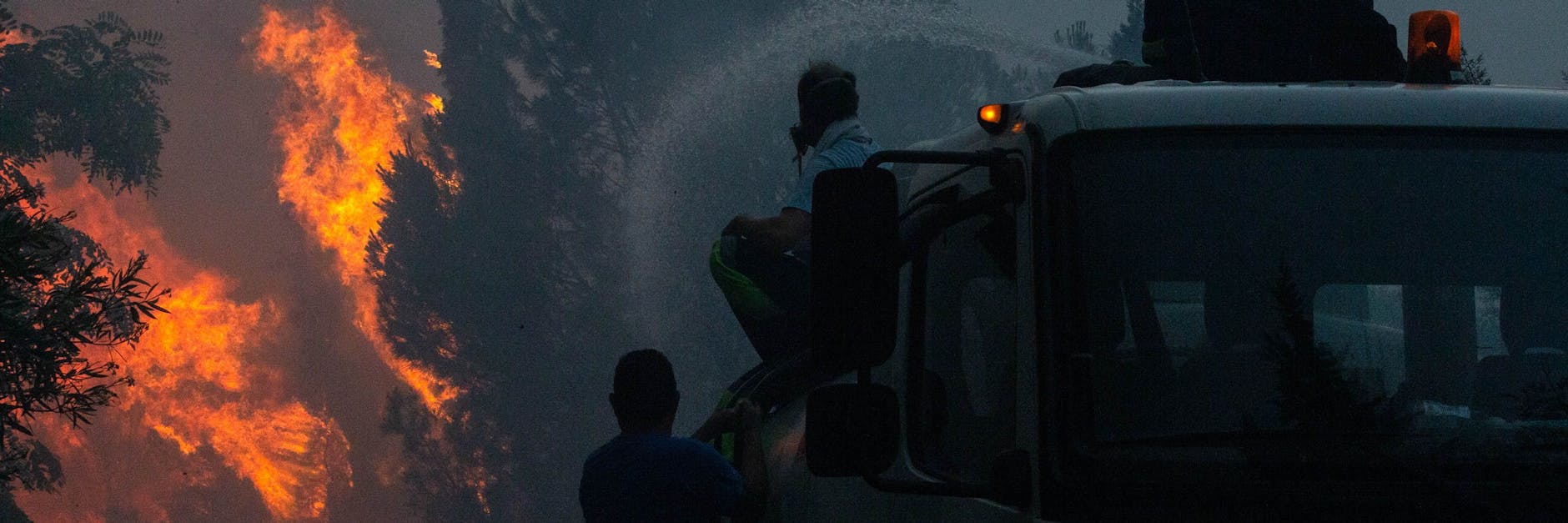 Feuerwehrleute sitzen auf einem Löschzug bei den Löscharbeiten eines Waldbrandes. Am Dienstagnachmittag brach an den Ausläufern des Berges Parnitha in der Gemeinde Acharnes, etwa 17 Kilometer nordöstlich von Athen, ein größerer Waldbrand aus. Das Feuer drohte auf Wohngebiete und nahe gelegene Reitsportzentren überzugreifen.