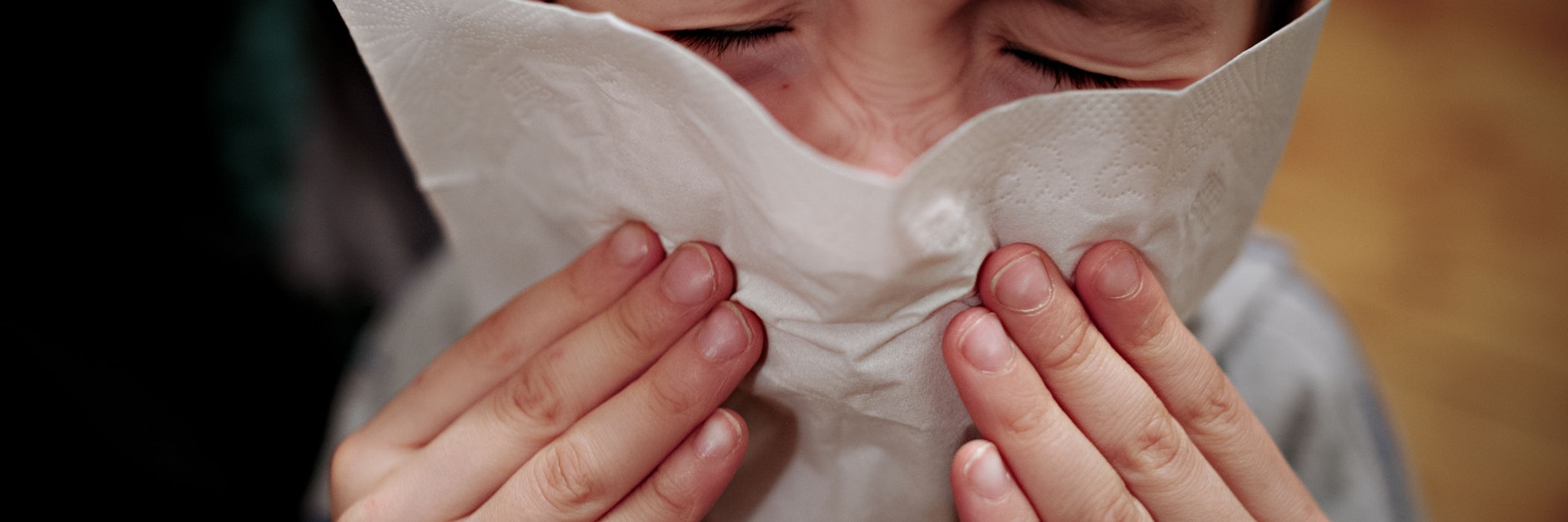 Ein kleiner Junge hält sich ein Taschentuch an die Nase.