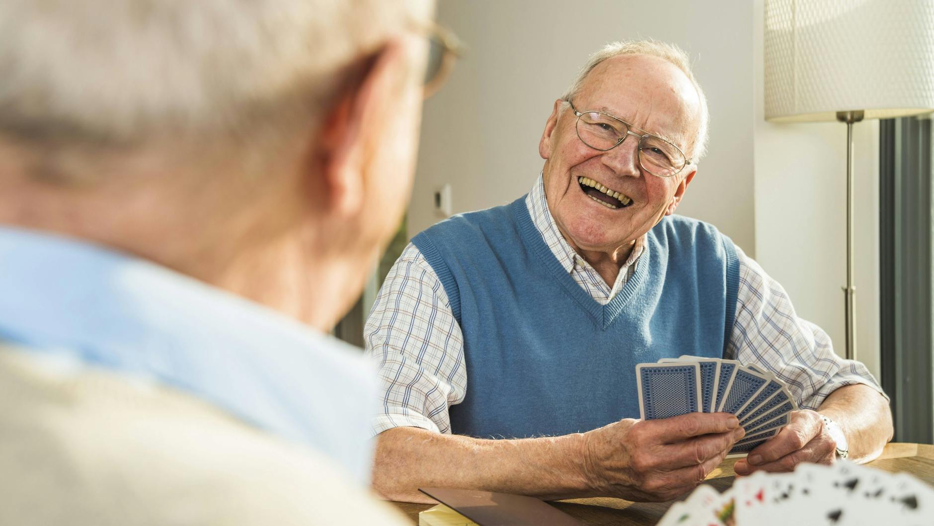 Zwei ältere Männer spielen Karten.