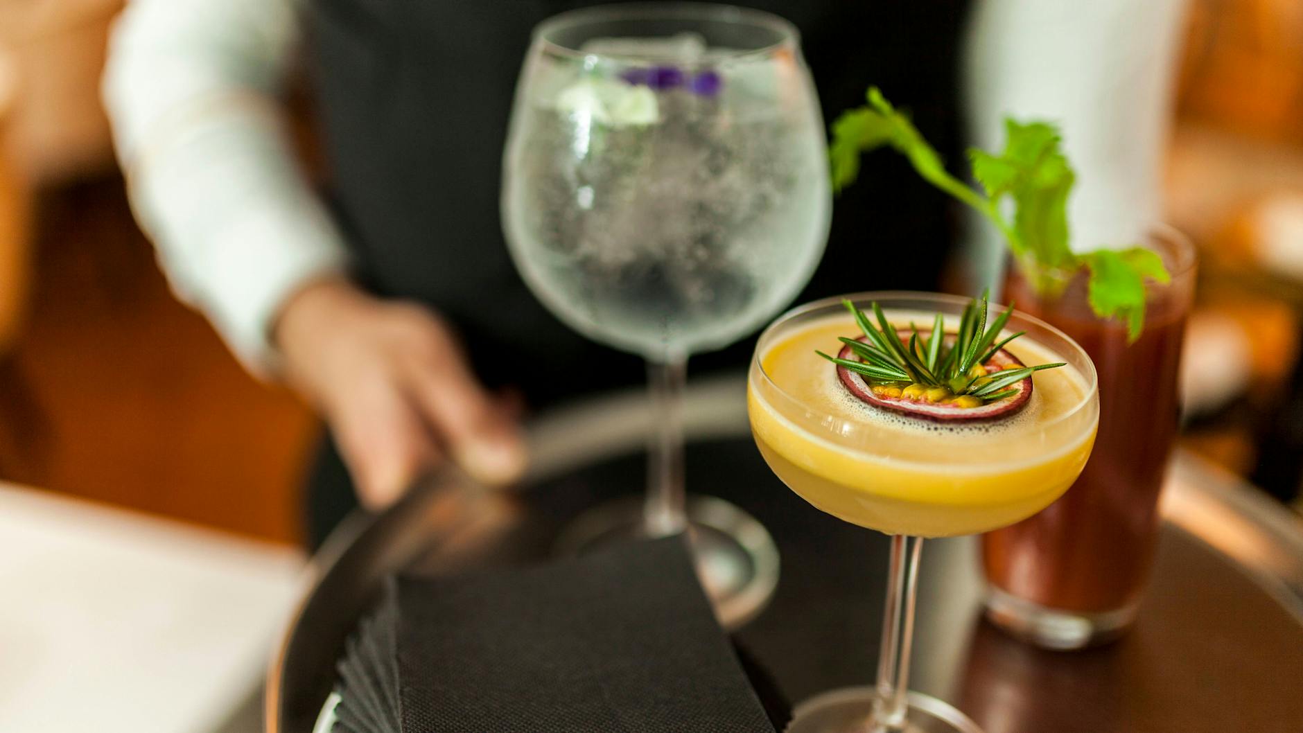Ein Kellner serviert Getränke auf einem Tablett (Symbolbild).