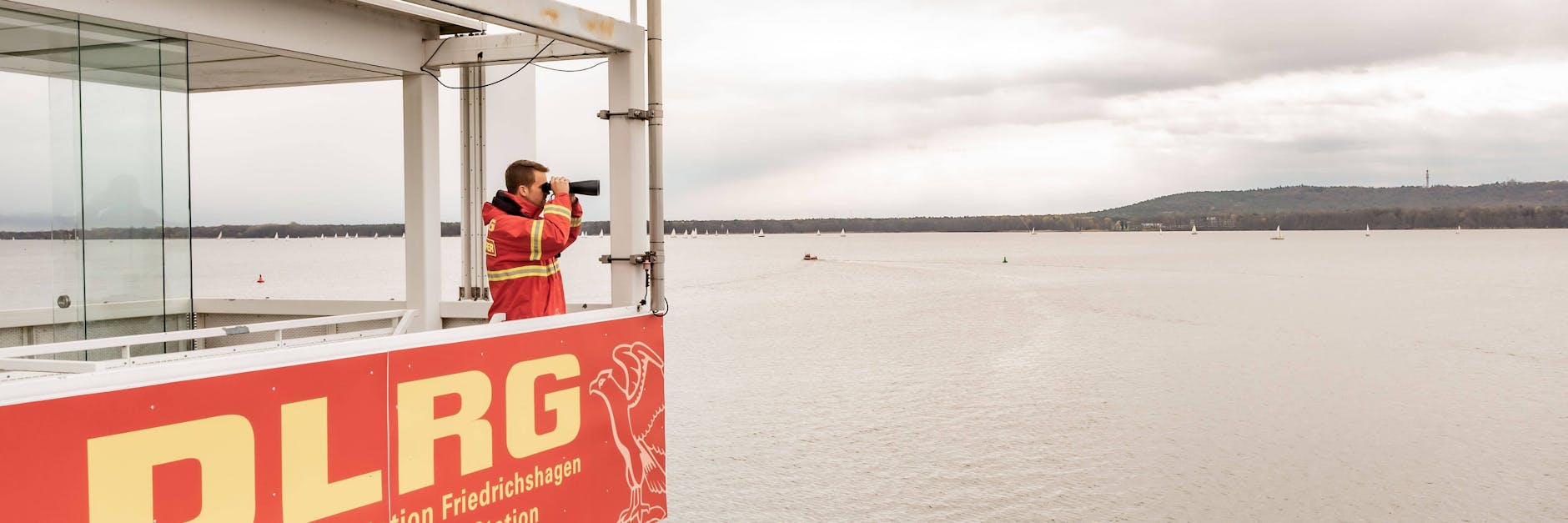 Ein DLRG-Mitarbeiter an der Rettungsstation in Berlin-Friedrichshagen hat den Müggelsee im Blick.