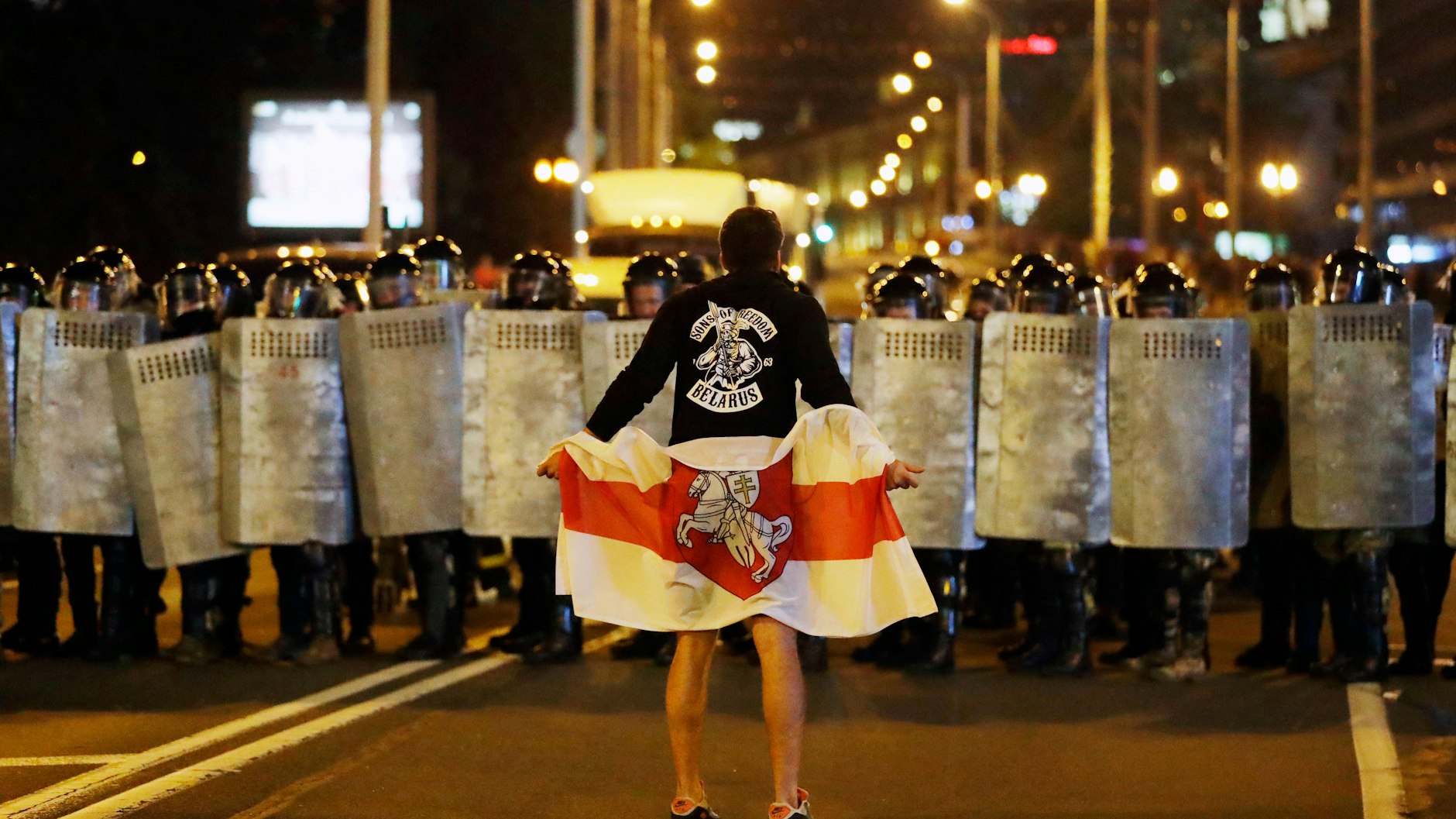 Eine Aufnahme vom 9. August 2020. Ein Demonstrant mit der weiß-rot-weißen Flagge der Demokratiebewegung vor einem Block von Polizisten.