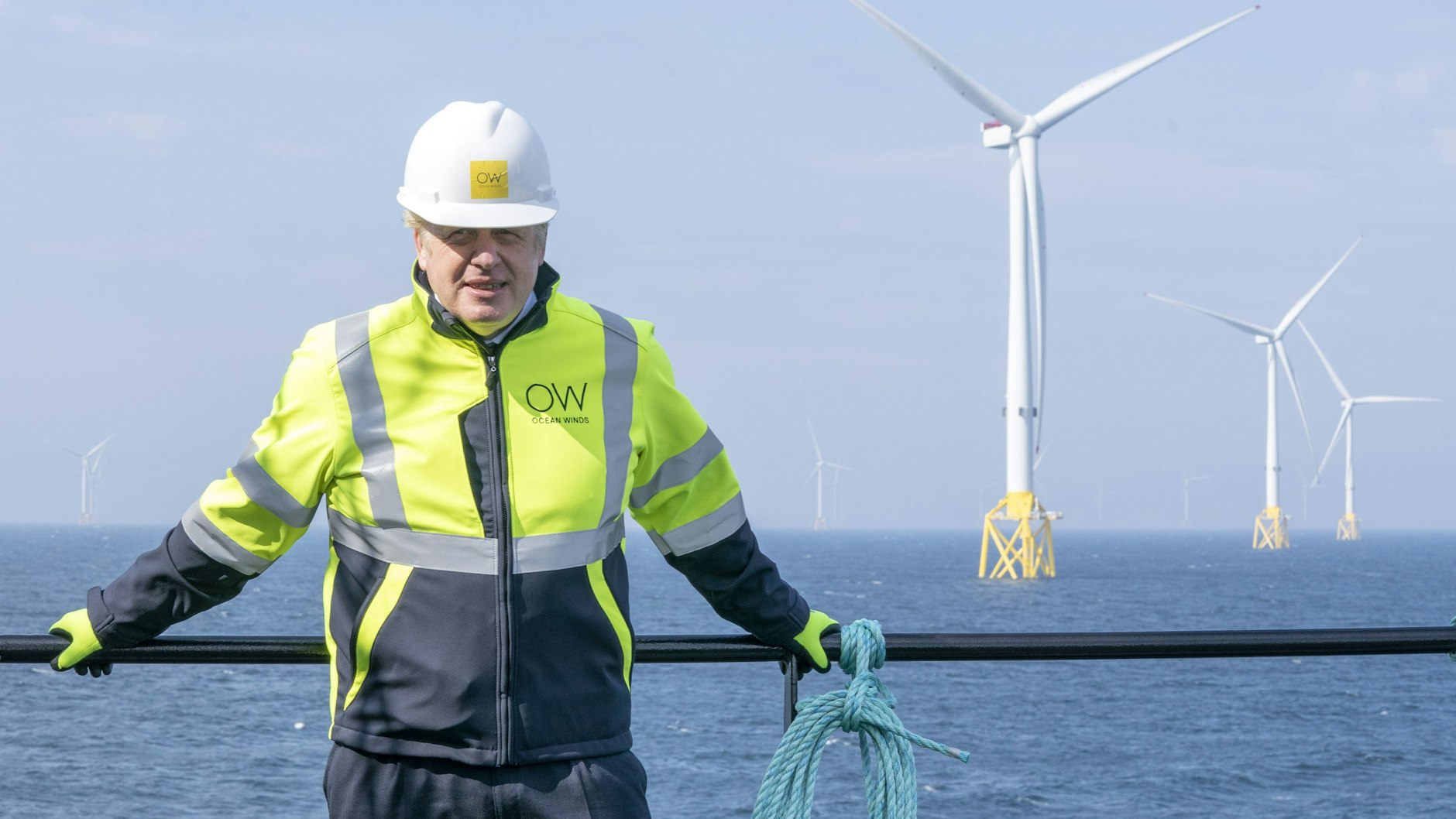 Boris Johnson, Premierminister von Großbritannien, trägt Schutzkleidung und einen Helm, als er am Deck des Schiffes „Esvagt Alba“ am Geländer steht und die Windparkanlange „Moray Offshore Windfarm East“, die im Hintergrund zu sehen ist, vor der Küste von Aberdeenshire besucht.
