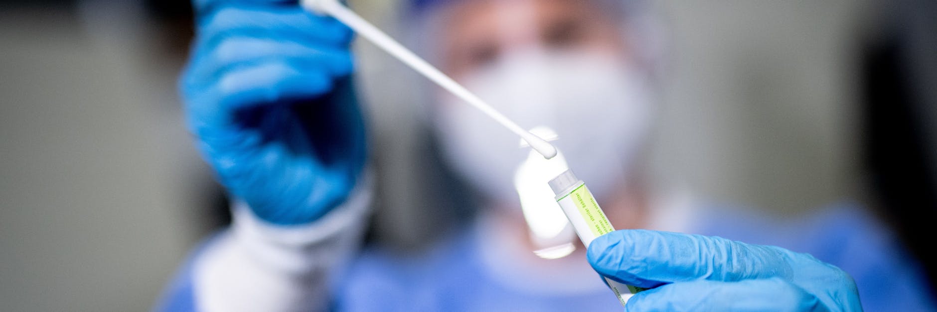 Eine Frau hält in einem Covid-19 Testcenter die Probe von einem Rachenabstrich in den Händen.