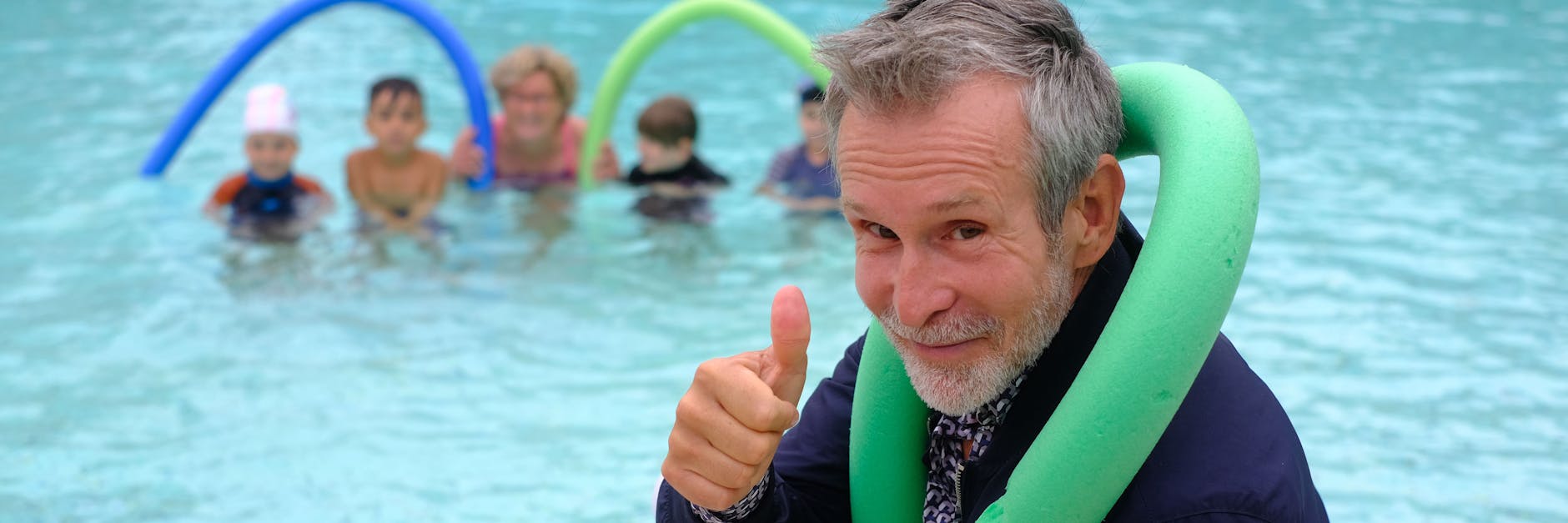 Schauspieler Ulrich Matthes sitzt als Schwimmpate im Sommerbad Wilmersdorf am Beckenrand und ist von den Schwimmkünsten der Mädchen und Jungen begeistert.<br><br>