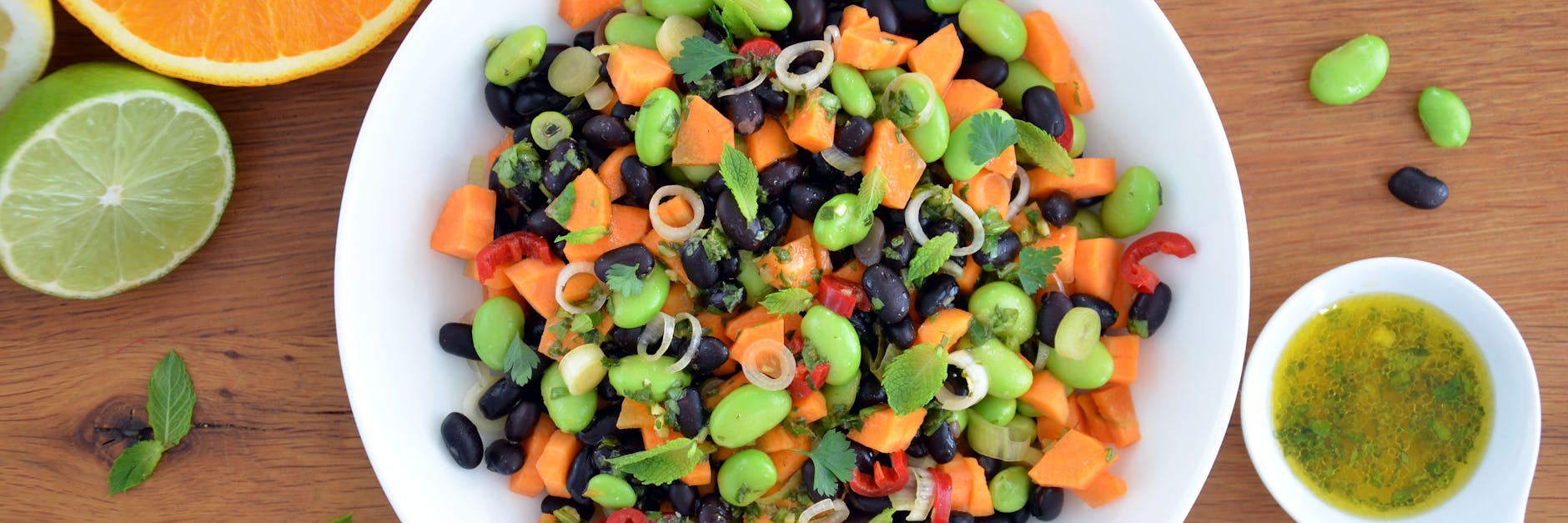 Leuchtend grüne Punkte vermischen sich mit dunklen und orangenen Farbtupfern: Zusammen mit dem Zitrusfrüchte-Dressing vermischt sich der nussig-würzige Bohnen-Mix zu einem frischen Salat.