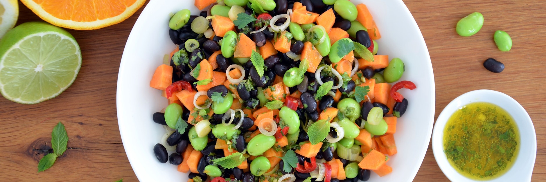 Leuchtend grüne Punkte vermischen sich mit dunklen und orangenen Farbtupfern: Zusammen mit dem Zitrusfrüchte-Dressing vermischt sich der nussig-würzige Bohnen-Mix zu einem frischen Salat.