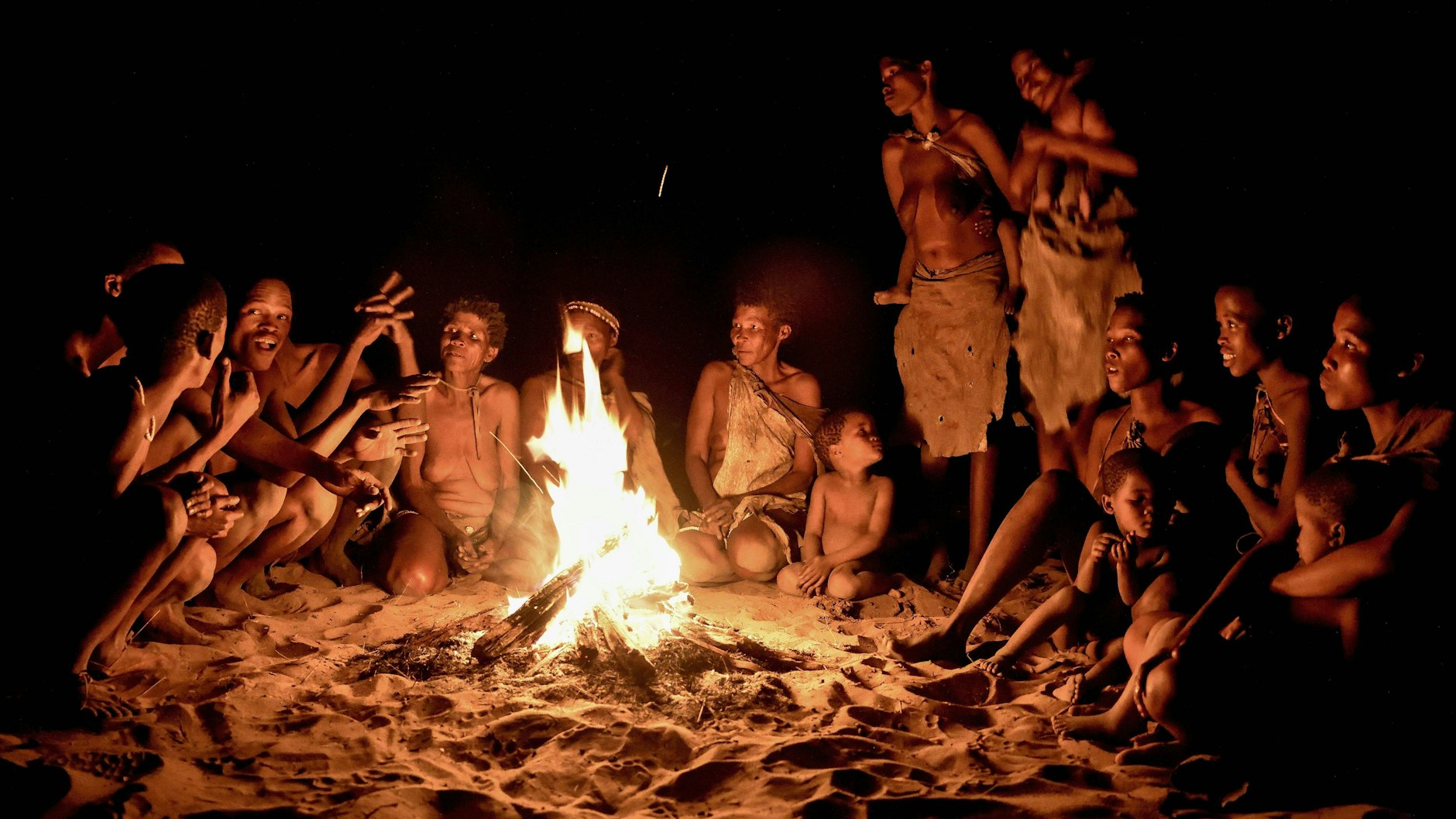 Mitglieder des Ju/’Hoansi-San sitzen am Lagerfeuer, Dorf bei Tsumkwe in Namibia.