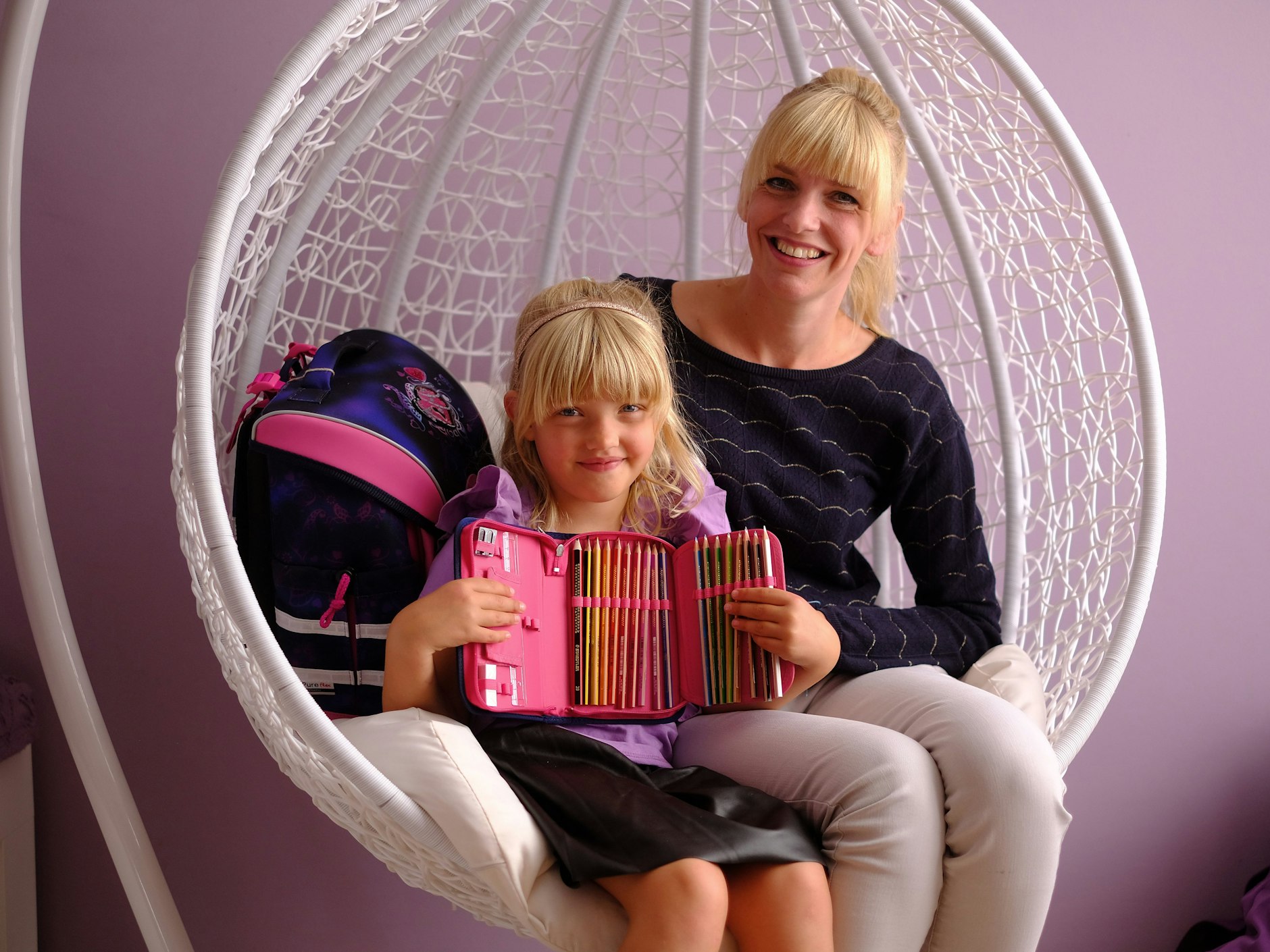 Marlene und ihre Mutter Monique im großen Korbsessel – Marlene zeigt ihr neues Federmäppchen.<br><br>