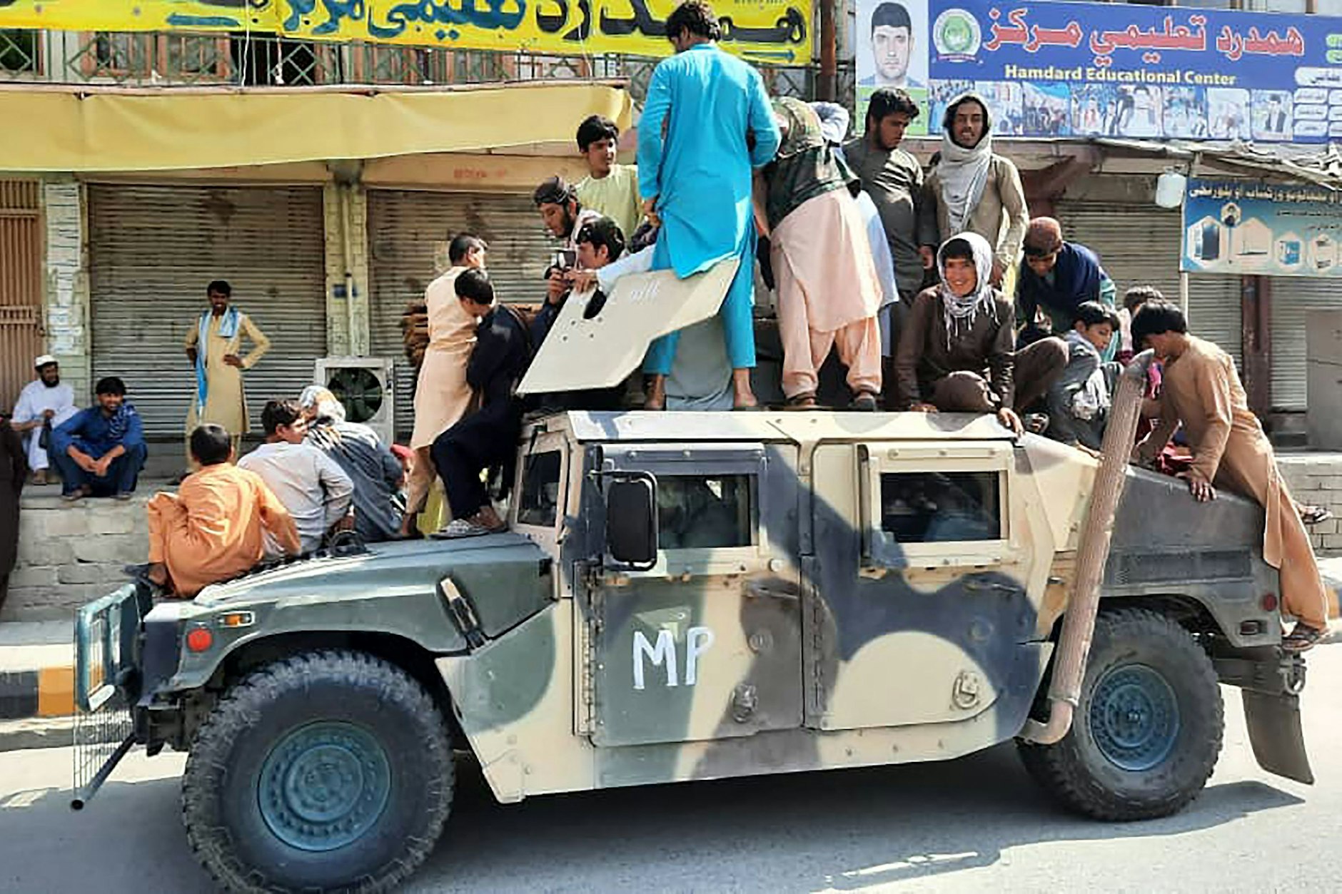 Taliban-Kämpfer und Anwohner sitzen auf einem erbeuteten Humvee der afghanische&nbsp;Armee.