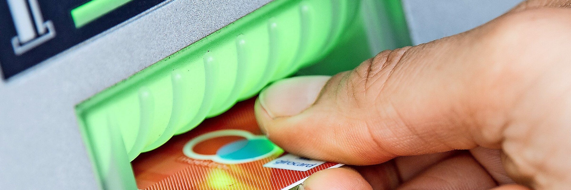 Eine Bankkundin steckt ihre Girokarte in einen Geldautomaten.&nbsp;