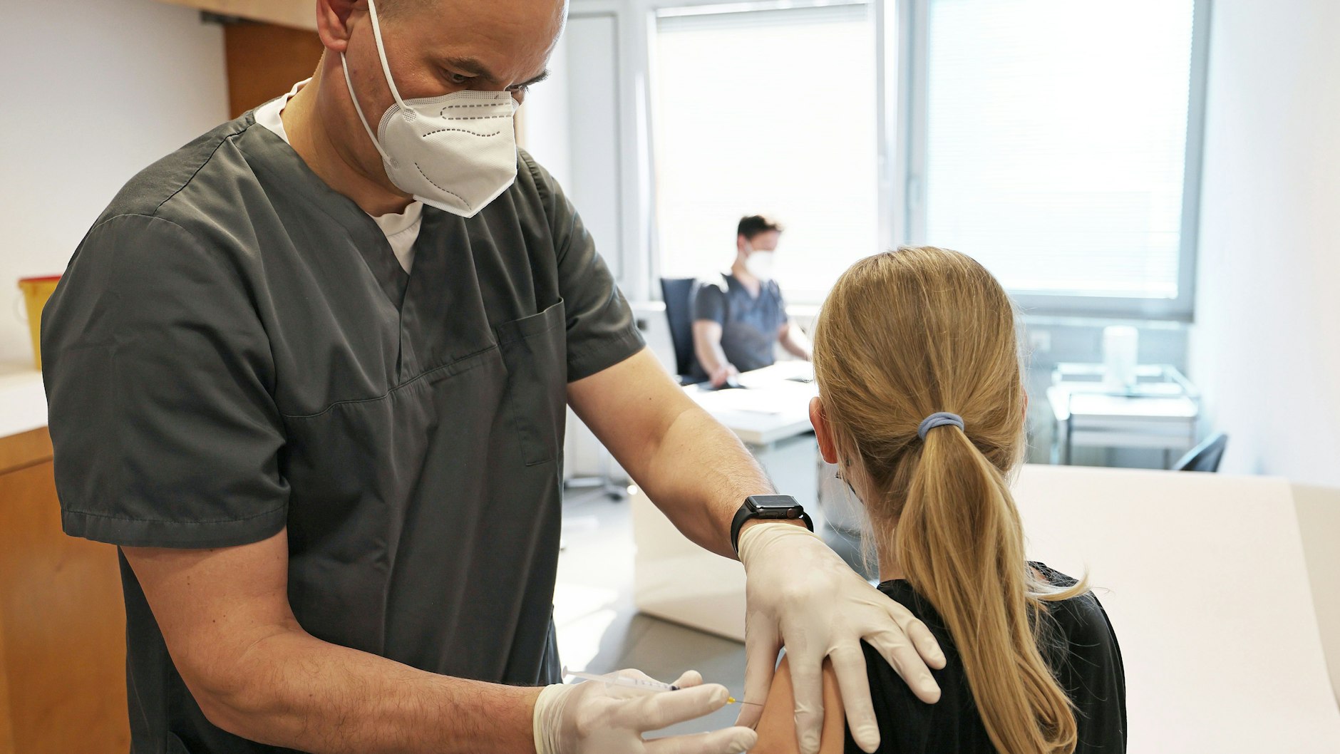 Ein zwölfjähriges Mädchen wird in einer Arztpraxis von dem Hausarzt Tim Koop (l) mit dem Serum von Biontech/Pfizer geimpft.