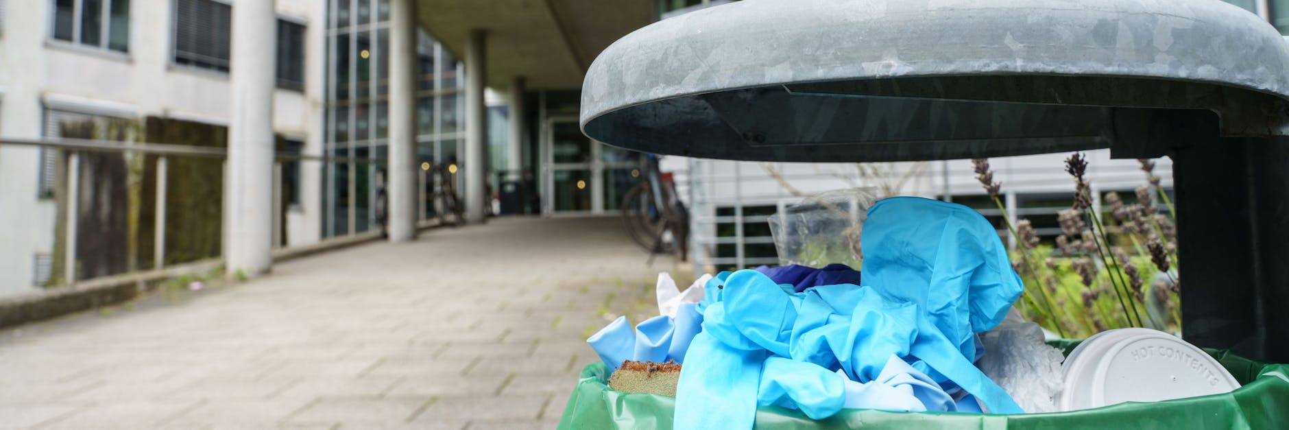 Benutzte Einweg-Handschuhe liegen in einem Abfallbehälter vor dem Gebäude L201 auf dem Campus Lichtwiese der Technischen Universität (TU) Darmstadt.