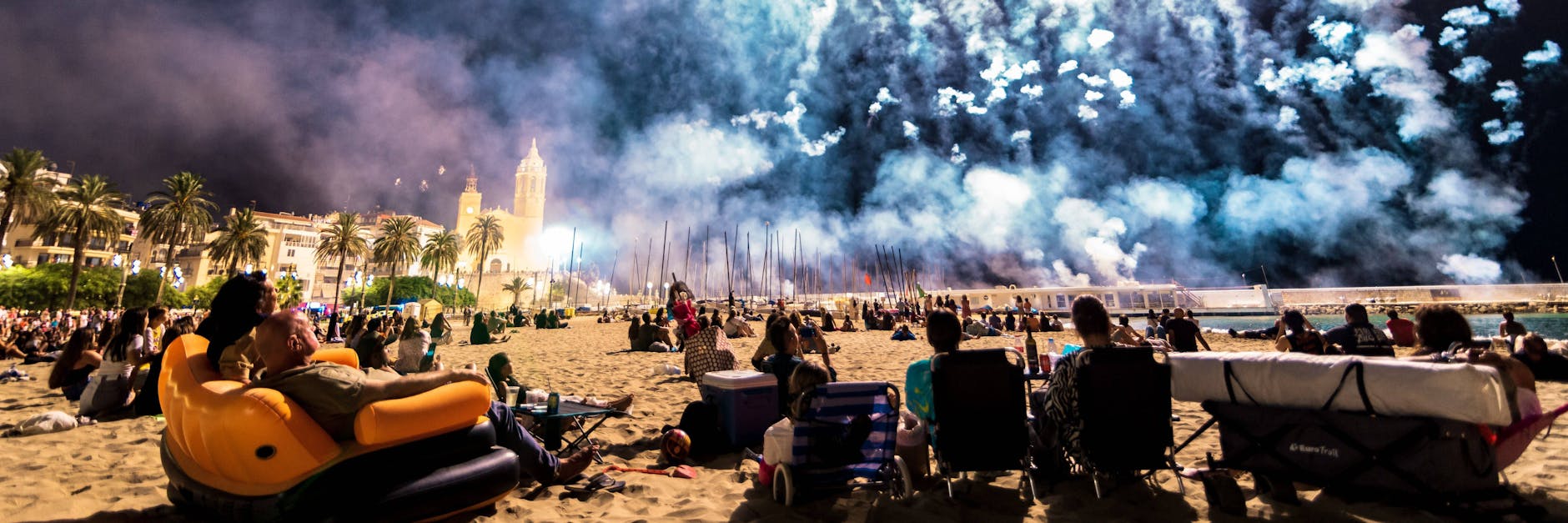 Am Montagabend in Sitges bei Barcelona in Spanien: Strandbesucher schauen sich ein Feuerwehr-Spektakel am Meer an.