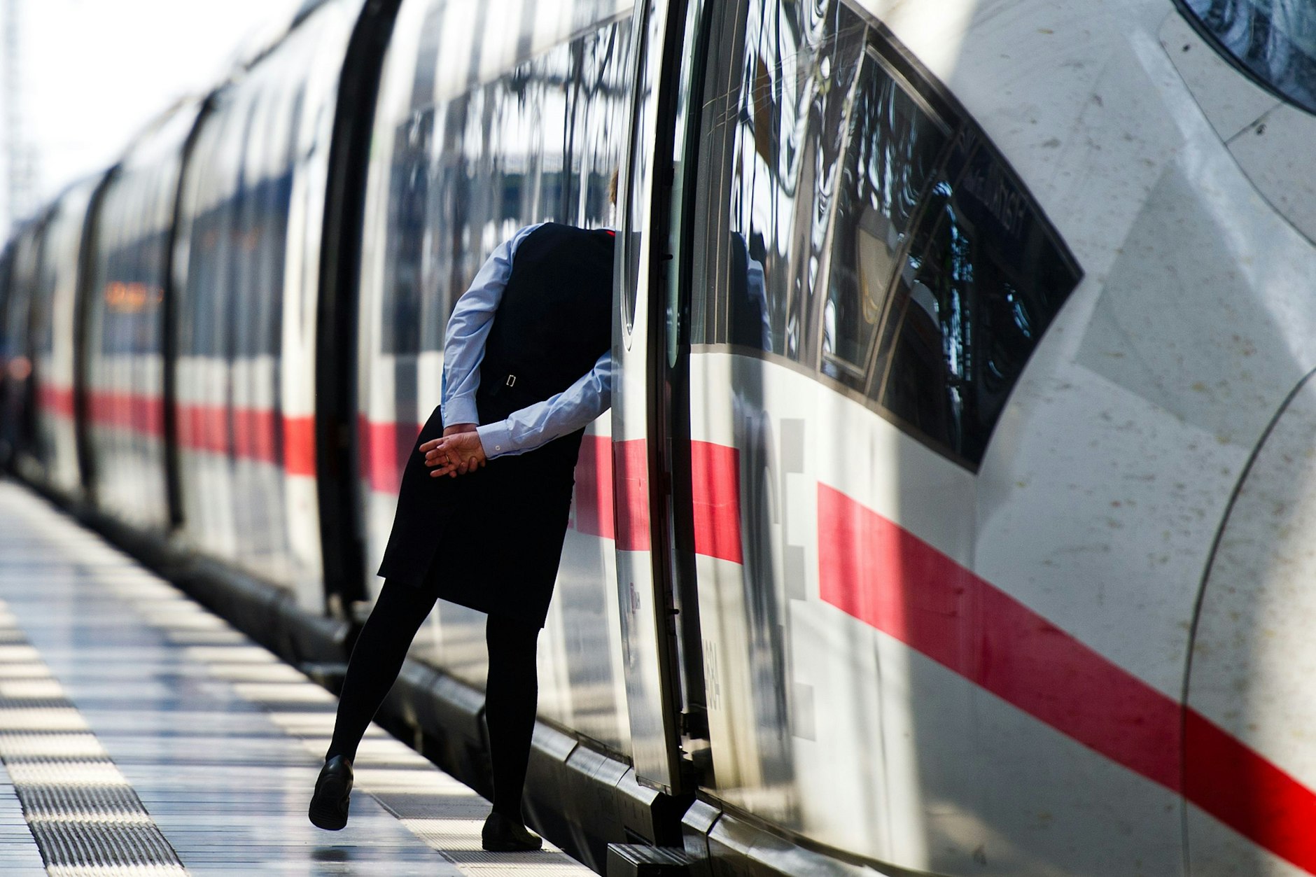 Eine Mitarbeiterin der Deutschen Bahn und ein ICE. In den letzten Jahren ist die Arbeitsbelastung des Zugpersonals immer größer geworden – die Zahl der Zugbegleiter dagegen immer kleiner. 