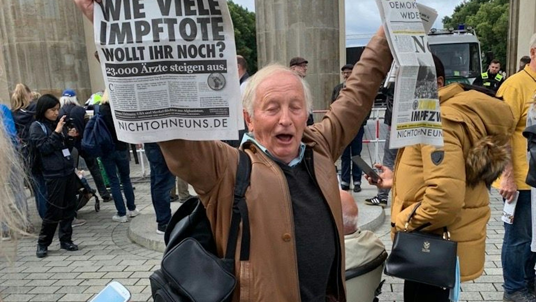 Ein Kritiker der Corona-Maßnahmen verteilt Zeitungen am Brandenburger Tor.