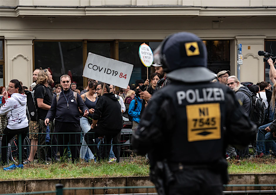 Ein Polizeibeamter steht auf der Danziger Straße vor einer Gruppe von Demonstranten gegen die Corona-Politik. Auch am Sonntag fanden in Berlin, teils trotz Verboten, Demonstrationen gegen die deutsche Corona-Politik statt.