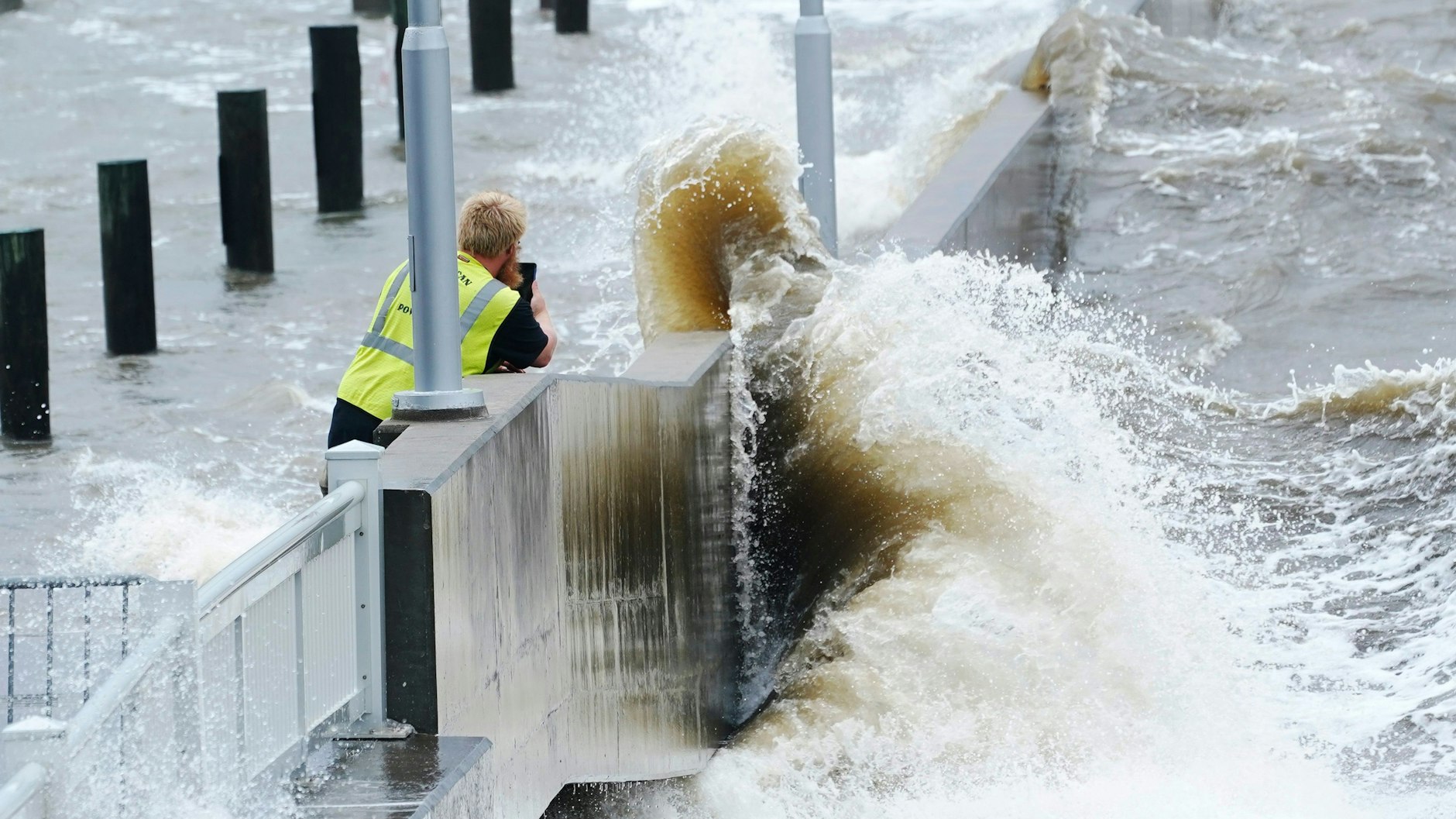 Ein Arbeiter eines Versorgungsunternehmens fotografiert die Wellen, die in Bay Saint Louis, Missouri, gegen eine Ufermauer im städtischen Jachthafen schlagen, während die äußeren Bänder des Hurrikans „Ida“ eintreffen.