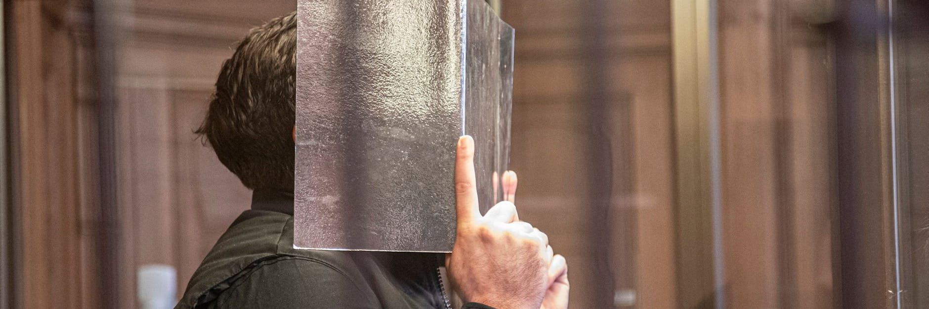 Der Angeklagte Muhamed R. (31) steht in einer Kabine aus Panzerglas vor Gericht.