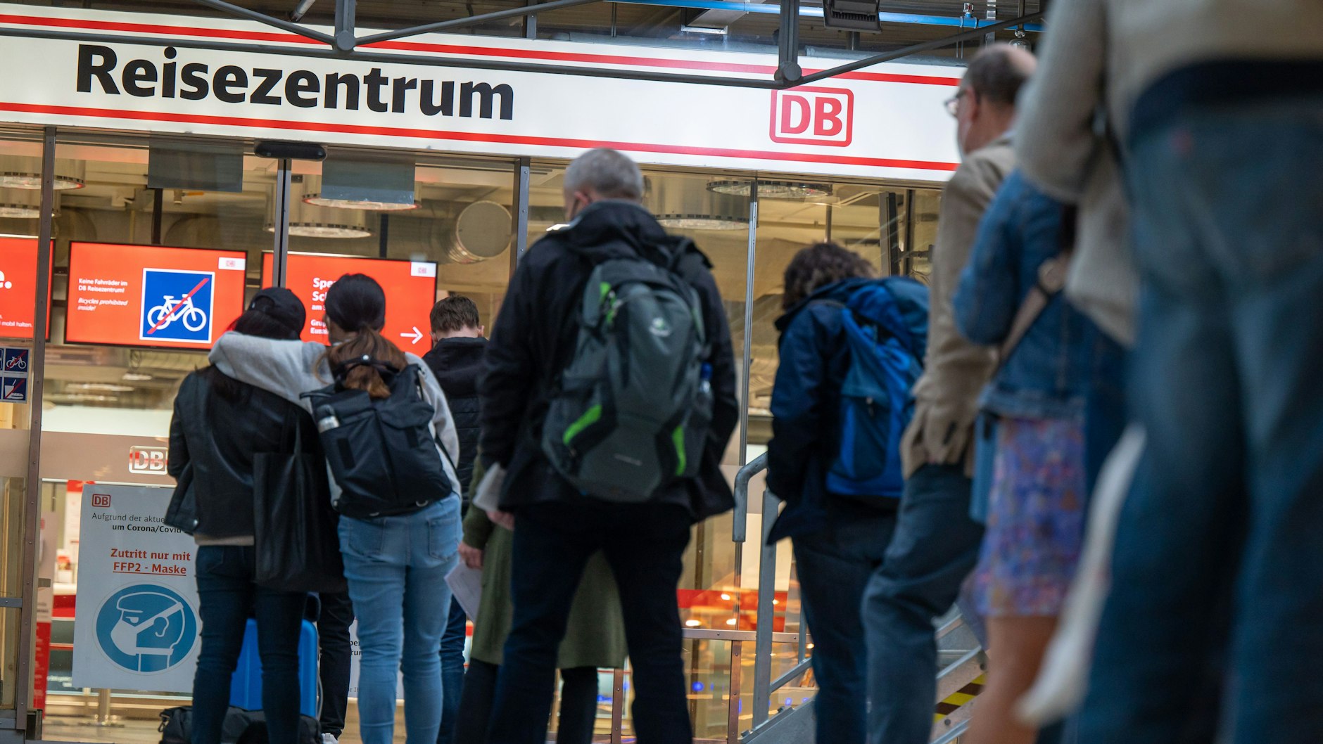 Bahnreisende warten vor einem Reisezentrum der Deutschen Bahn.