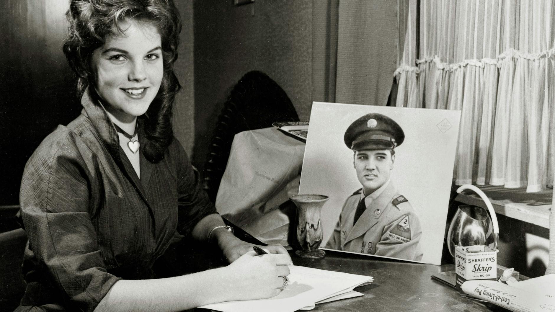 Die 16-jährige Priscilla sitzt neben einem Bild von Elvis in Militäruniform.