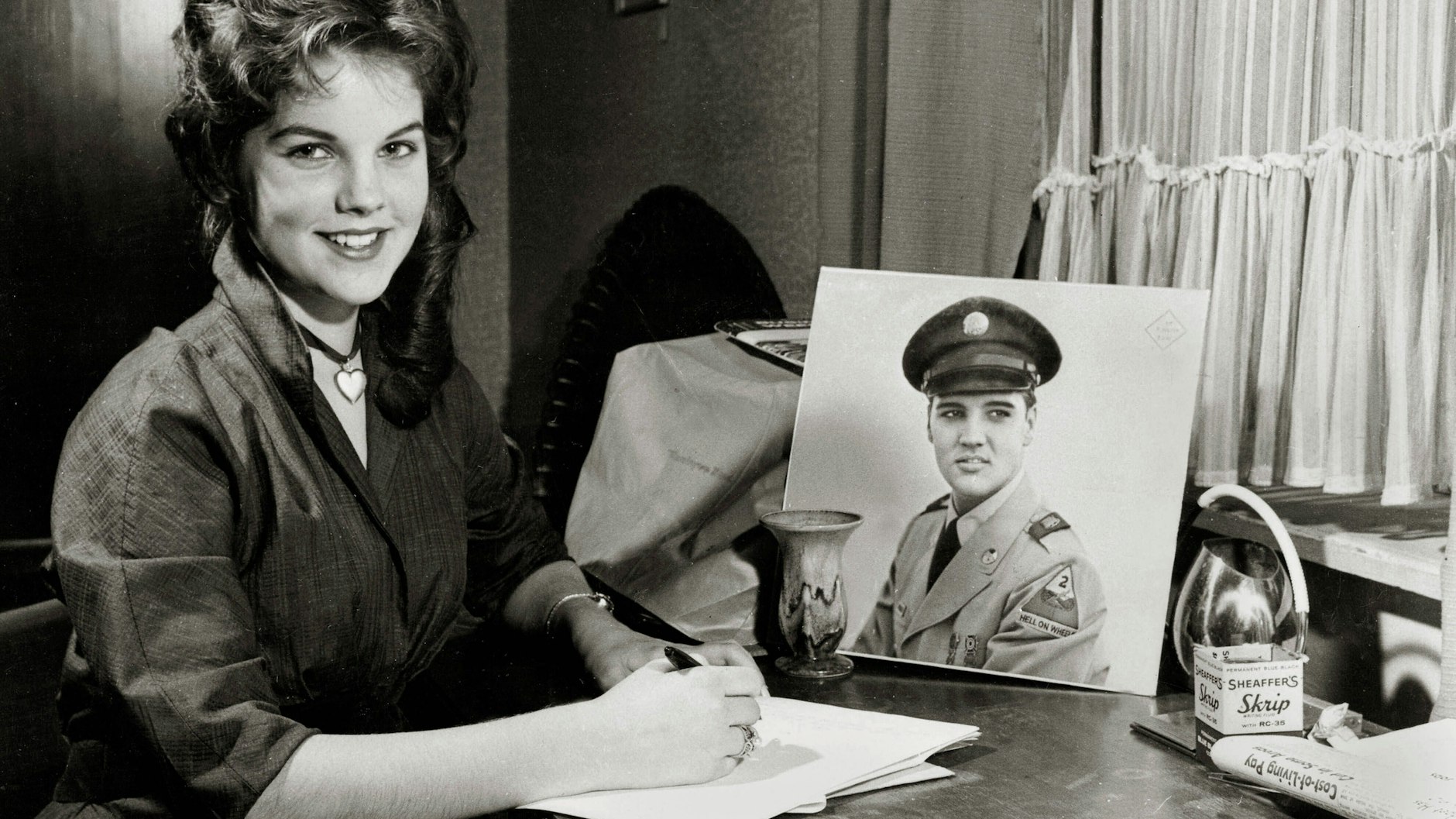 Die 16-jährige Priscilla sitzt neben einem Bild von Elvis in Militäruniform.