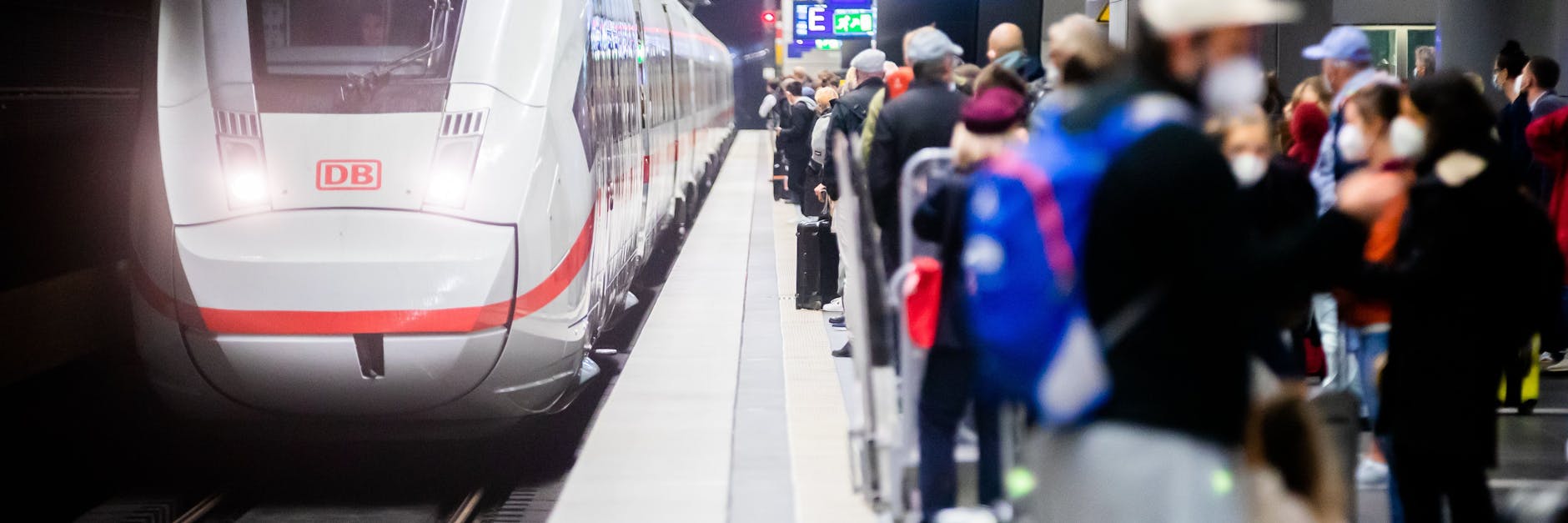 Zahlreiche Fahrgäste stehen am Berliner Hauptbahnhof am Bahnsteig, als ein ICE einfährt.