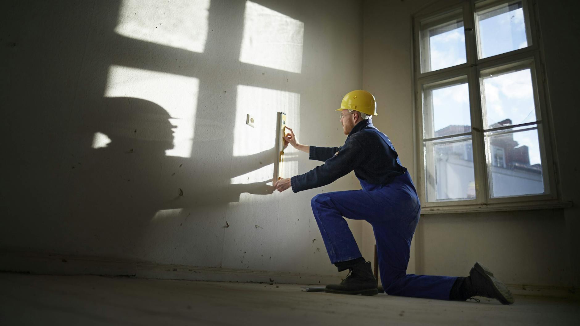 Bauarbeiter mit Wasserwaage bei der Sanierung eines Altbaus