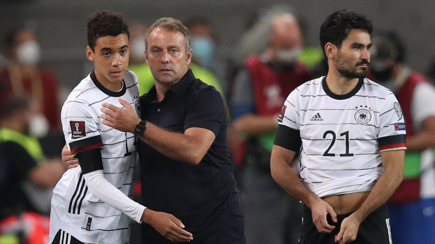 Deutschlands Trainer Hansi Flick (M.) umarmt Jamal Musiala (l.) vor dessen Einwechslung.