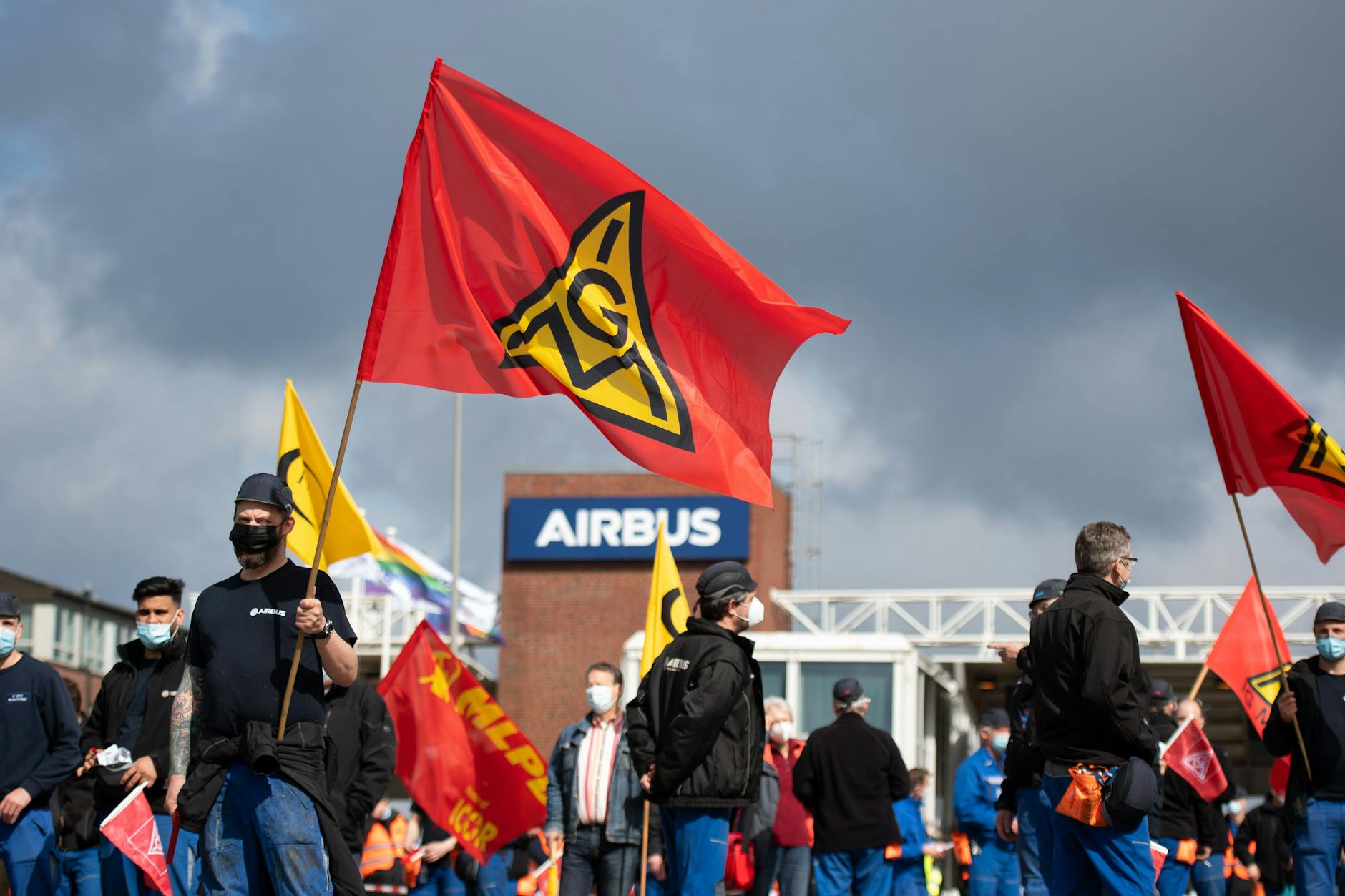Beschäftigte des Airbus-Werkes in Finkenwerder stehen vor den Toren des Werksgeländes und schwenken Fahnen der IG Metall. Die deutschen Airbus-Belegschaften und die Gewerkschaften laufen Sturm gegen Umbaupläne des Flugzeugbauers.