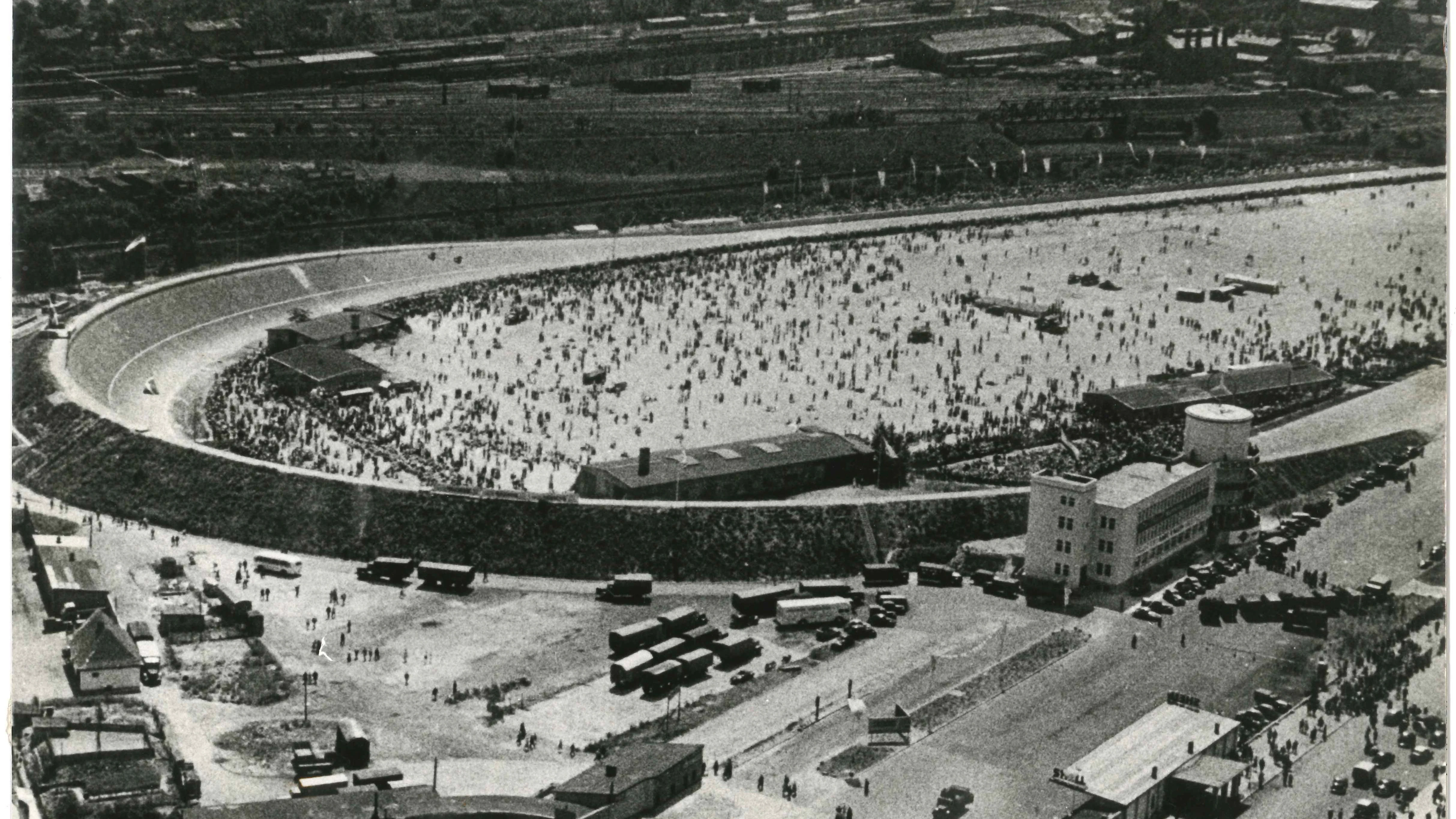 Als die alte Avus-Nordkurve noch stand: Das historische Bild zeigt, wie viele Menschen einst zu den Rennen auf der Avus kamen. Rechts steht das einstige Verwaltungsgebäude mit dem Zielrichterturm, heute das Motel Avus.