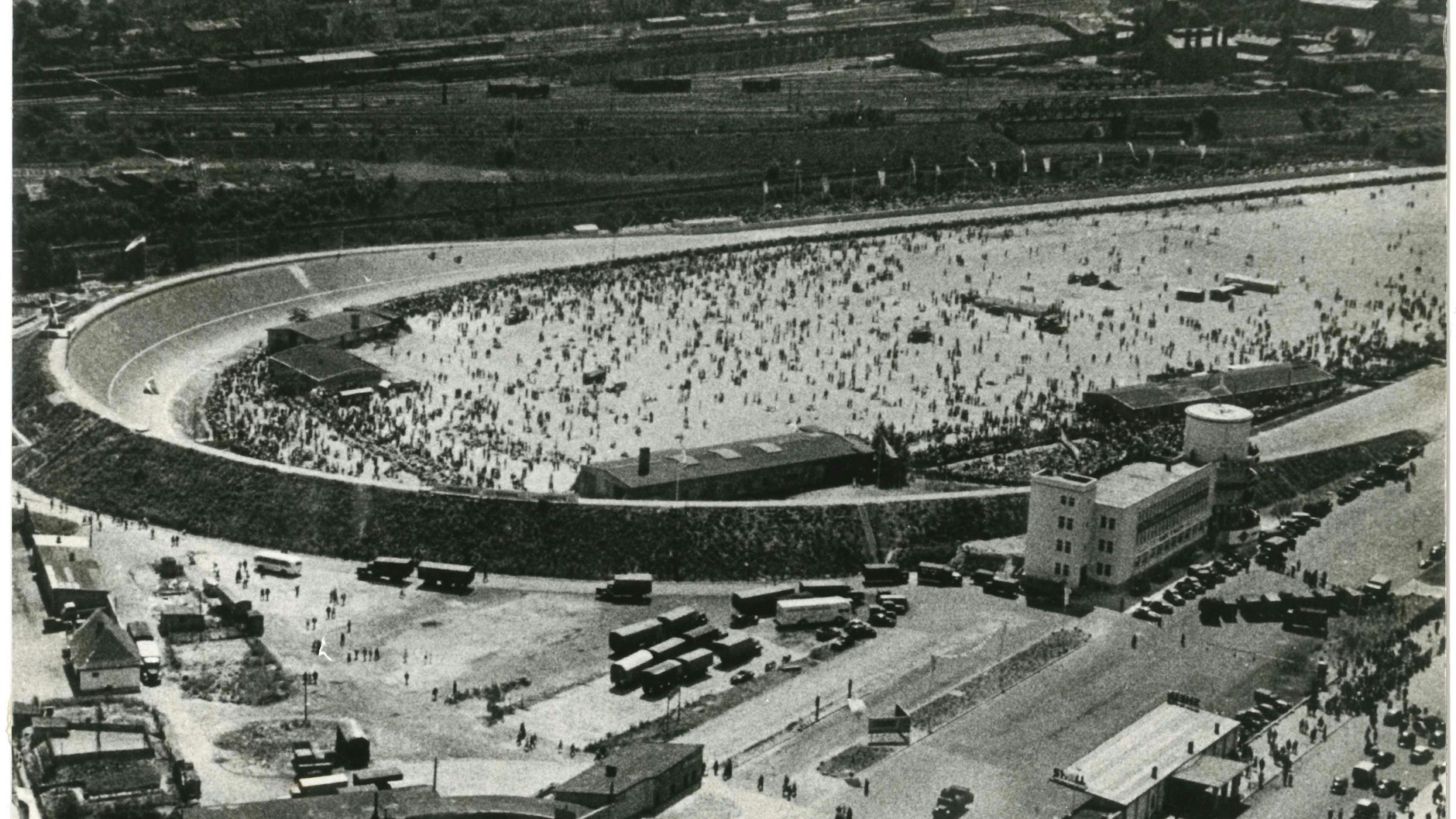 Als die alte Avus-Nordkurve noch stand: Das historische Bild zeigt, wie viele Menschen einst zu den Rennen auf der Avus kamen. Rechts steht das einstige Verwaltungsgebäude mit dem Zielrichterturm, heute das Motel Avus.