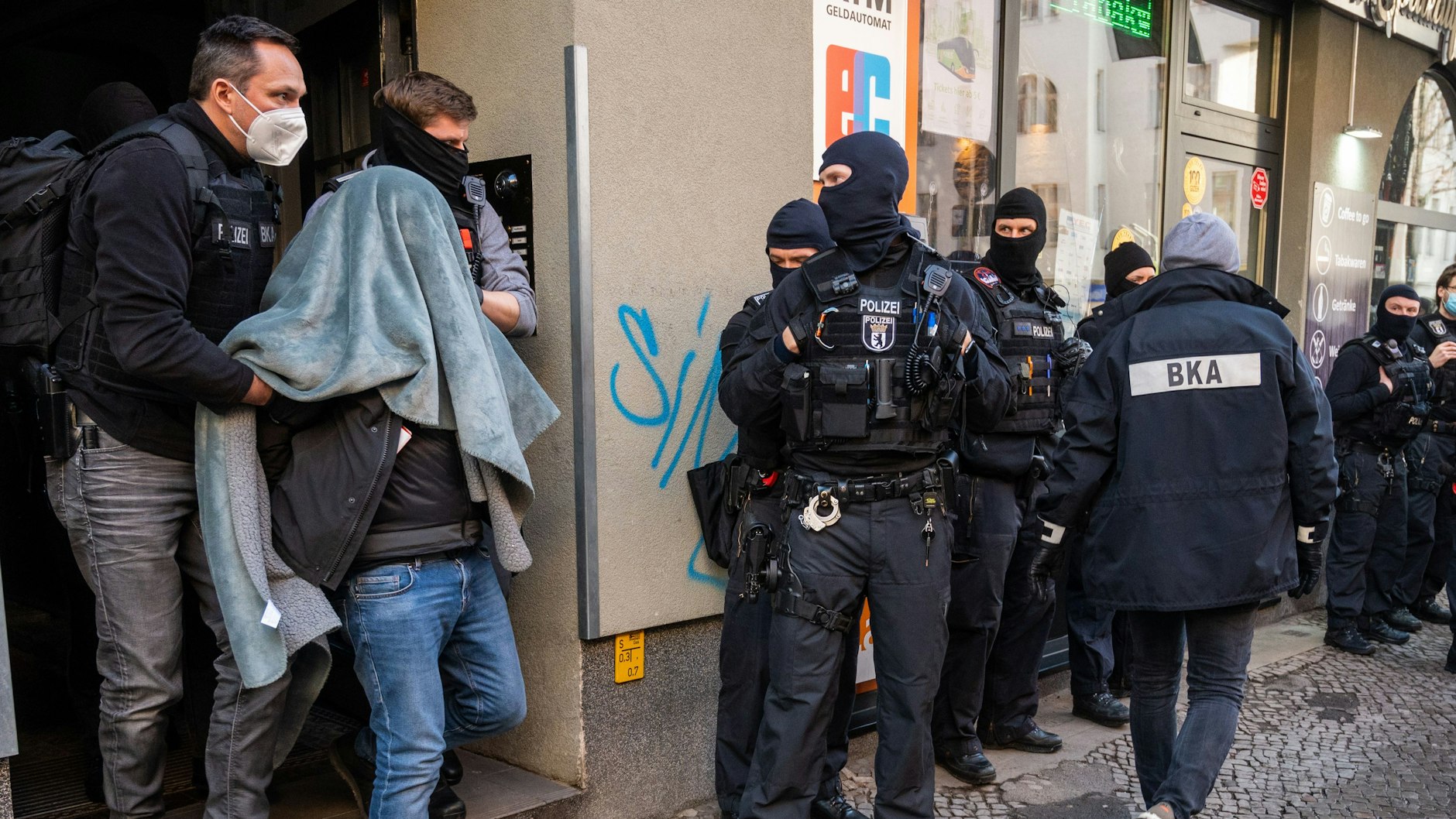 Ein Mann wird bei einer Razzia in Berlin mit einer Decke über dem Kopf von der Polizei abgeführt, nachdem Ermittler die Software Encrochat gehackt hatten.&nbsp;