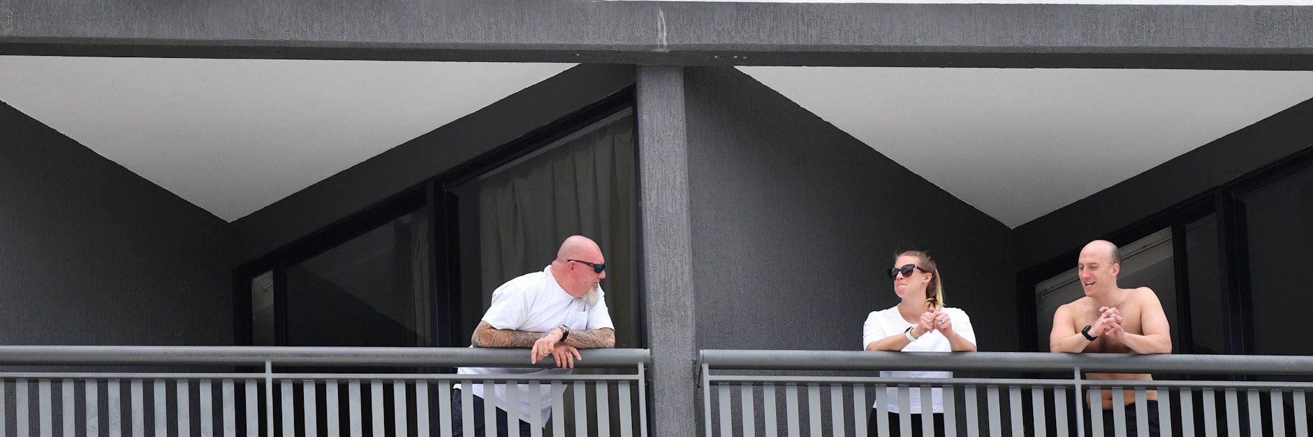 Urlauber in einem Quarantäne-Hotel unterhalten sich auf den Balkonen.