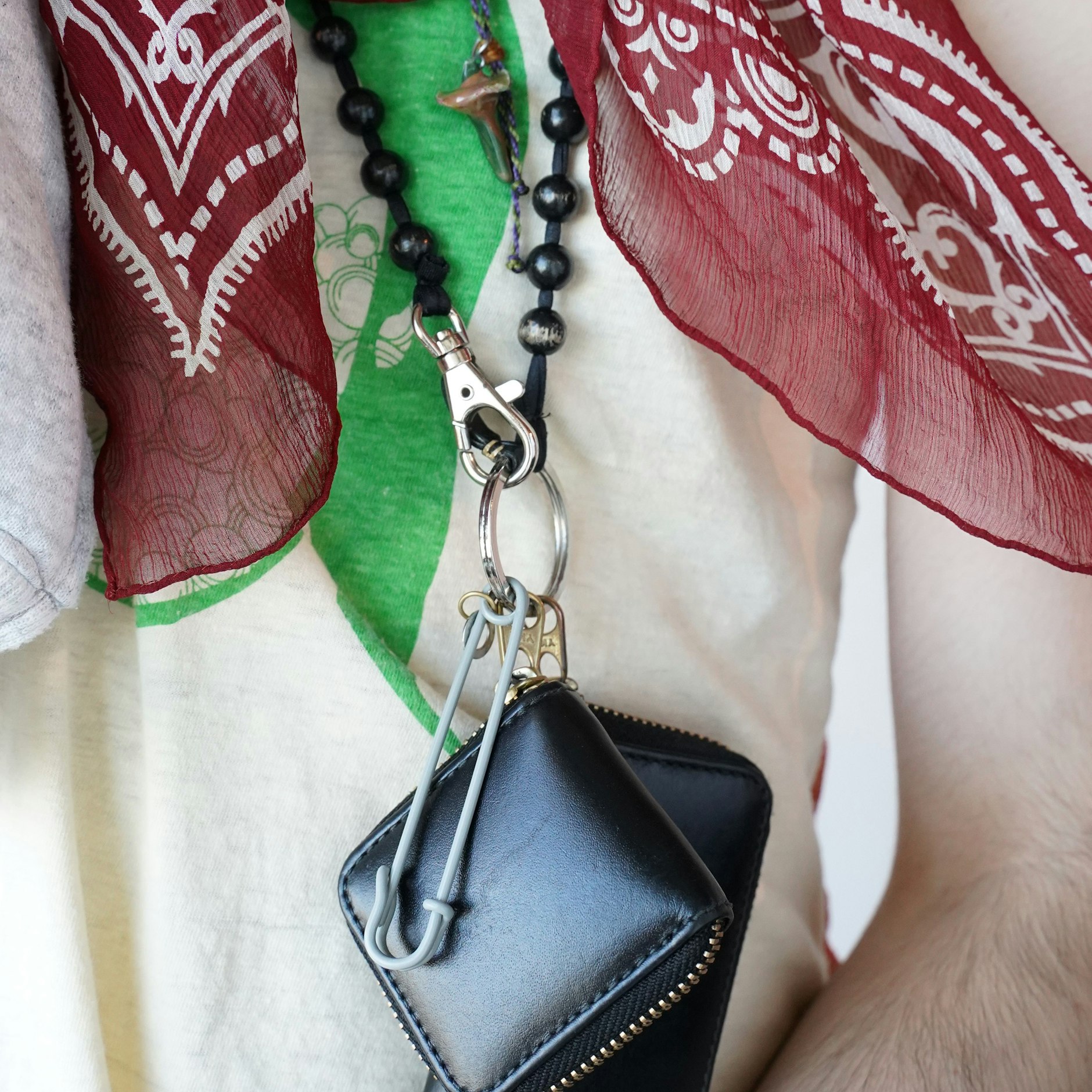 ... und um den Hals, an der Holzperlenkette von Ina Seifart, zwei Zippertäschchen von&nbsp;Comme des Garçons und eine grau lackierte Sicherheitsnadel des Berliner Labels Bless.