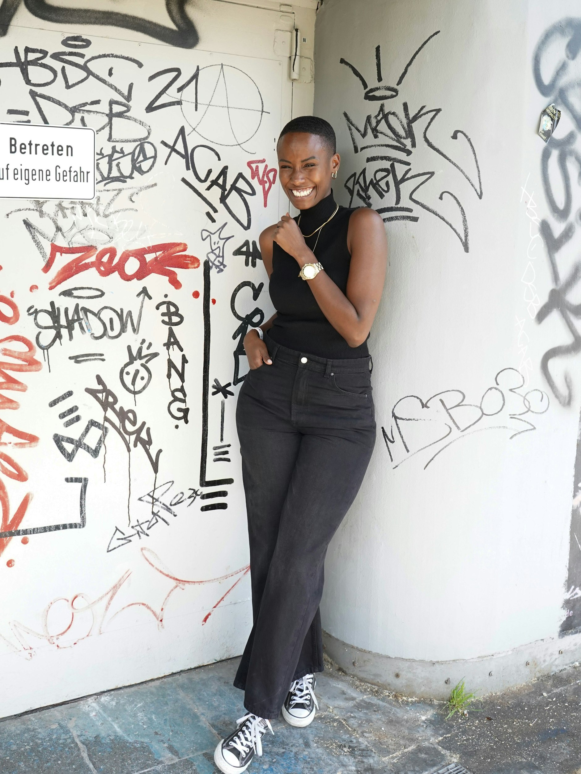 Melissa studiert Psychologie und arbeitet nebenbei im Security-Bereich. Heute steht sie an der Festival-Tür und zeigt sich ganz in ihrer Lieblingsfarbe Schwarz. Zum superkurzen Haar trägt sie ein geripptes Tanktop von Zara, eine Vintage-Jeans und Chucks.