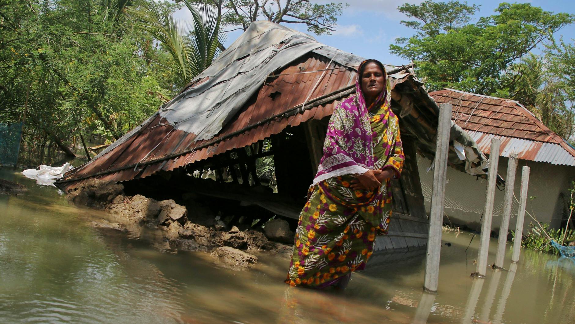 Eine Frau steht in Bangladesh vor ihrem Laden, der von der Flutwelle des Zyklons Amphan 2020 zerstört wurde. Die Corona-Pandemie hat die Folgen der Katastrophe noch verschlimmert.