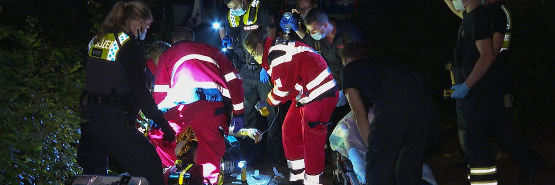 Hamburg: Sanitäter und Polizisten bemühen sich in der Nacht um eine verletzte Person.