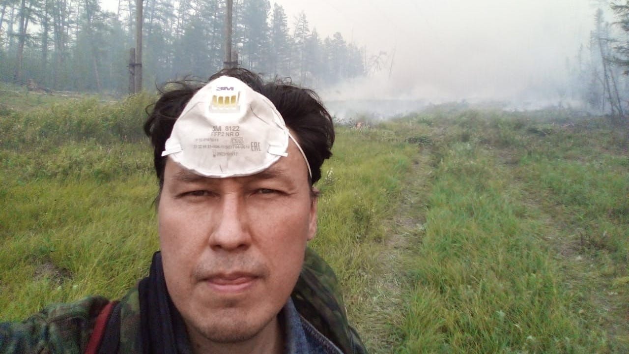 Albert Wassiljew steht in einem Wald in der russischen teilrepublik Jakutien, wo er immer wieder gegen Waldbrände kämpft.