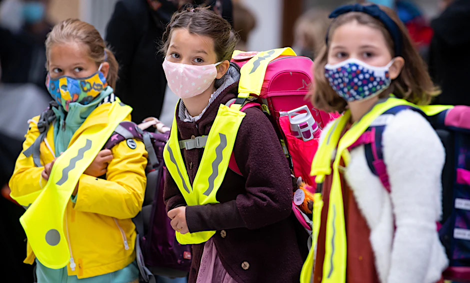 Maskierte Grundschulkinder auf dem Weg in die Schule.