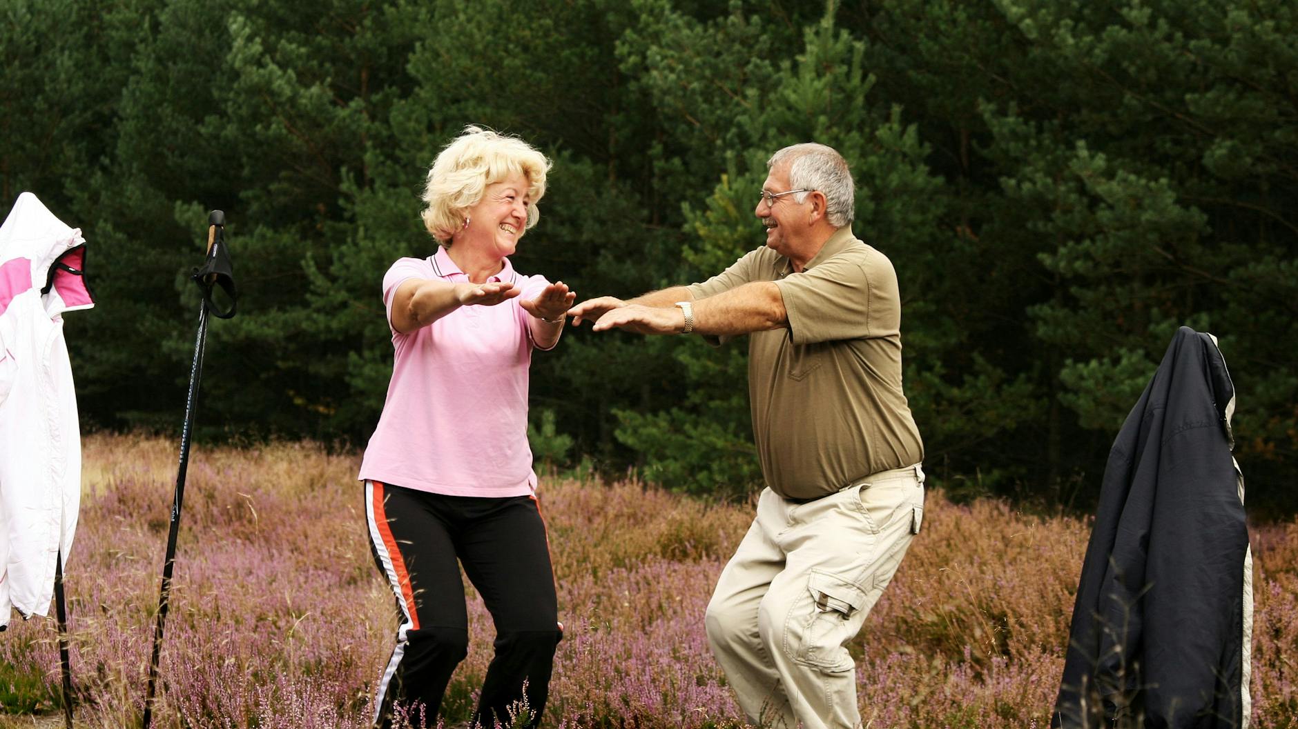 Ein Paar vergnügt sich während einer Walking Runde bei der Übung Kniebeuge.