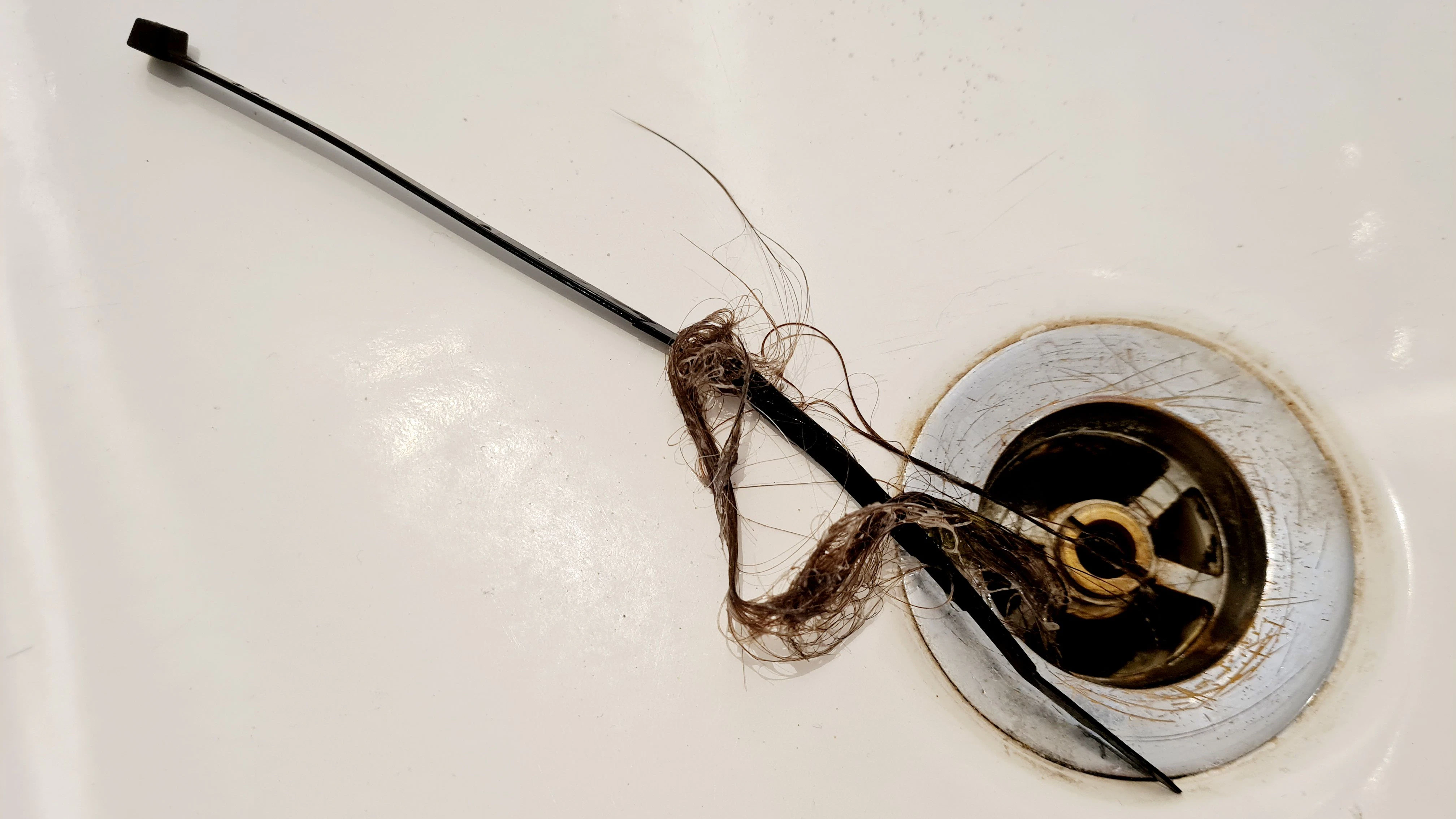 Einen verstopften Abfluss im Bad kann man mit einem Kabelbinder von Haarknäulen befreien.