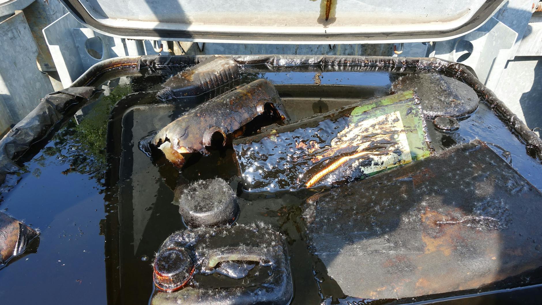 In den feuerverzinkten Containern schwappt dunkles Altöl herum, die Sicherheitsverriegelung steht offen.
