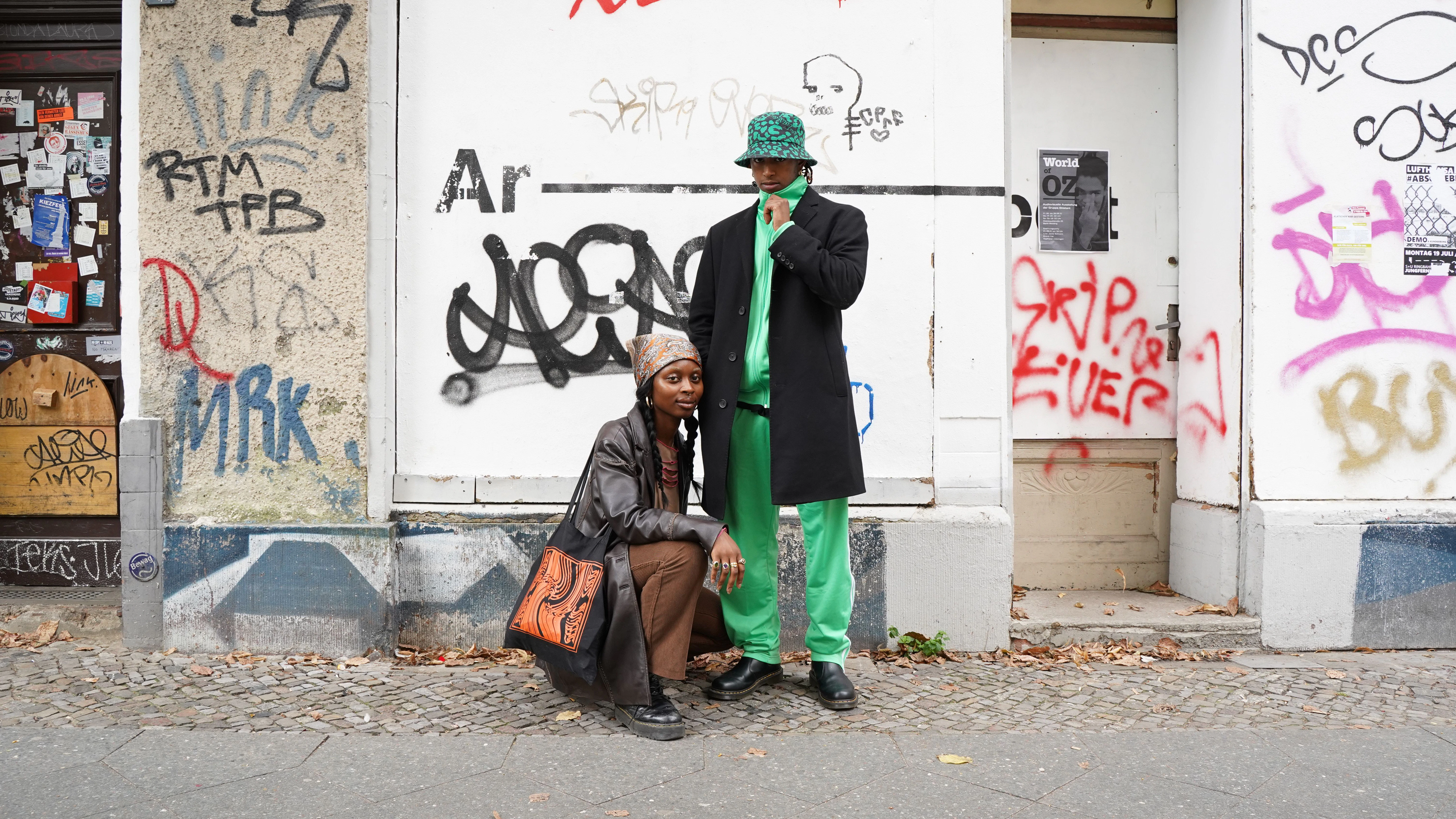 Olivia und Jewel sind befreundet und haben sich gerade zufällig auf der Malplaquetstraße getroffen. Olivias Ledermantel, Top und Hose sind Vintage.&nbsp;Jewel ist Creative Director im Film- und Fashionbereich. Der grüne Trainingsanzug stammt aus der 2021er adidas-Originals-Kollektion, Mantel und Hut sind Vintage.&nbsp;
