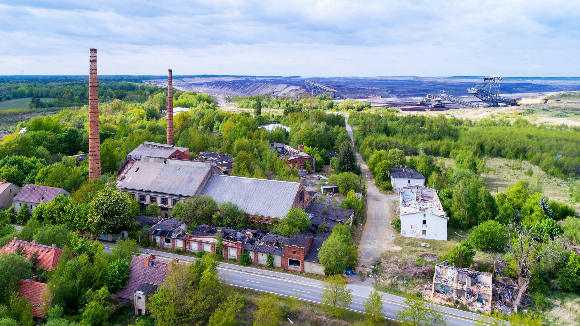 Mit einer Drohne fotografiert sieht das riesige Areal fast malerisch aus. Im Hintergrund schaufeln sich riesige Tagebau-Bagger dröhnend durch den Braunkohleflöz. 